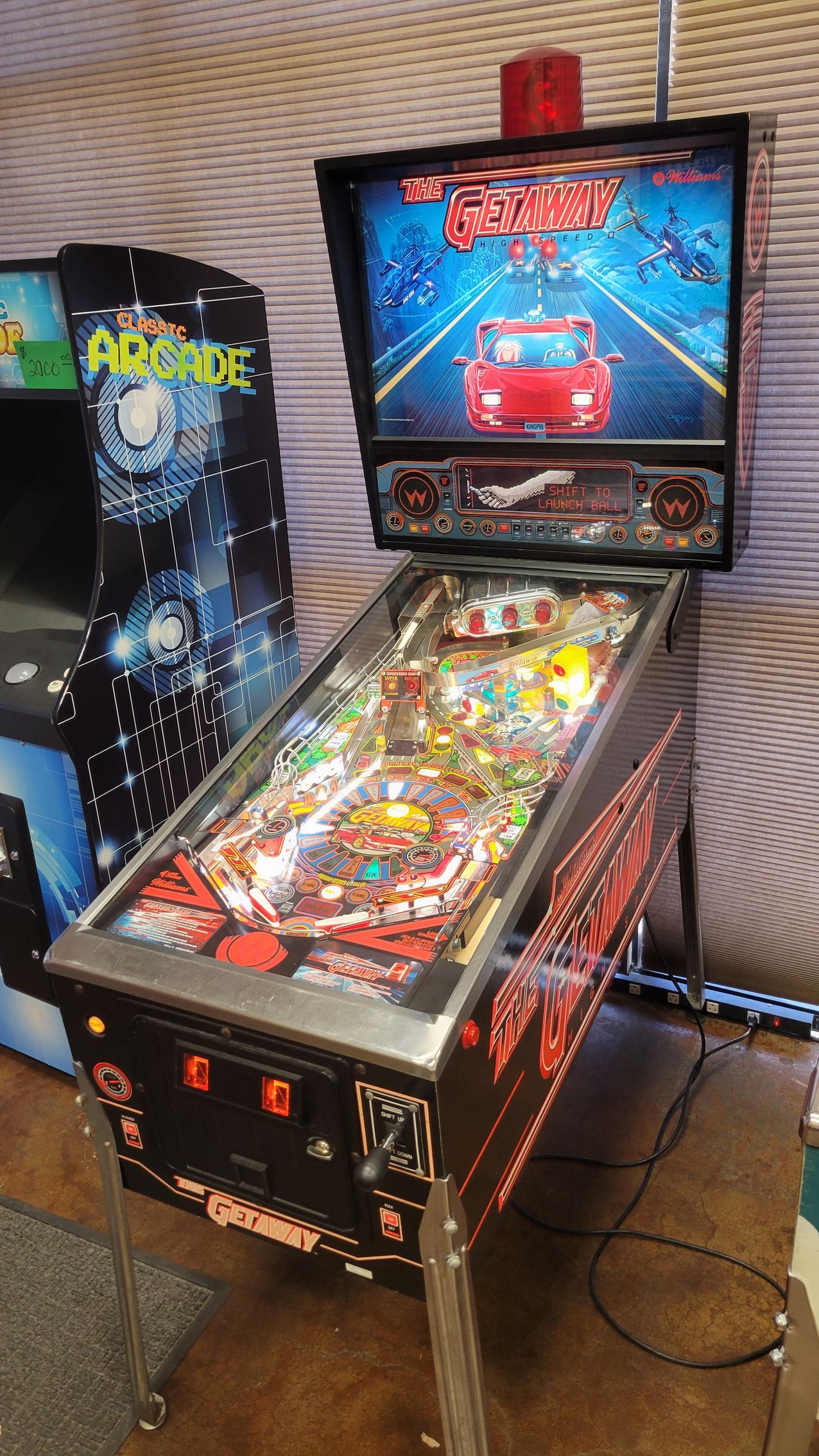 A pinball machine is sitting on a wooden floor next to an arcade machine.