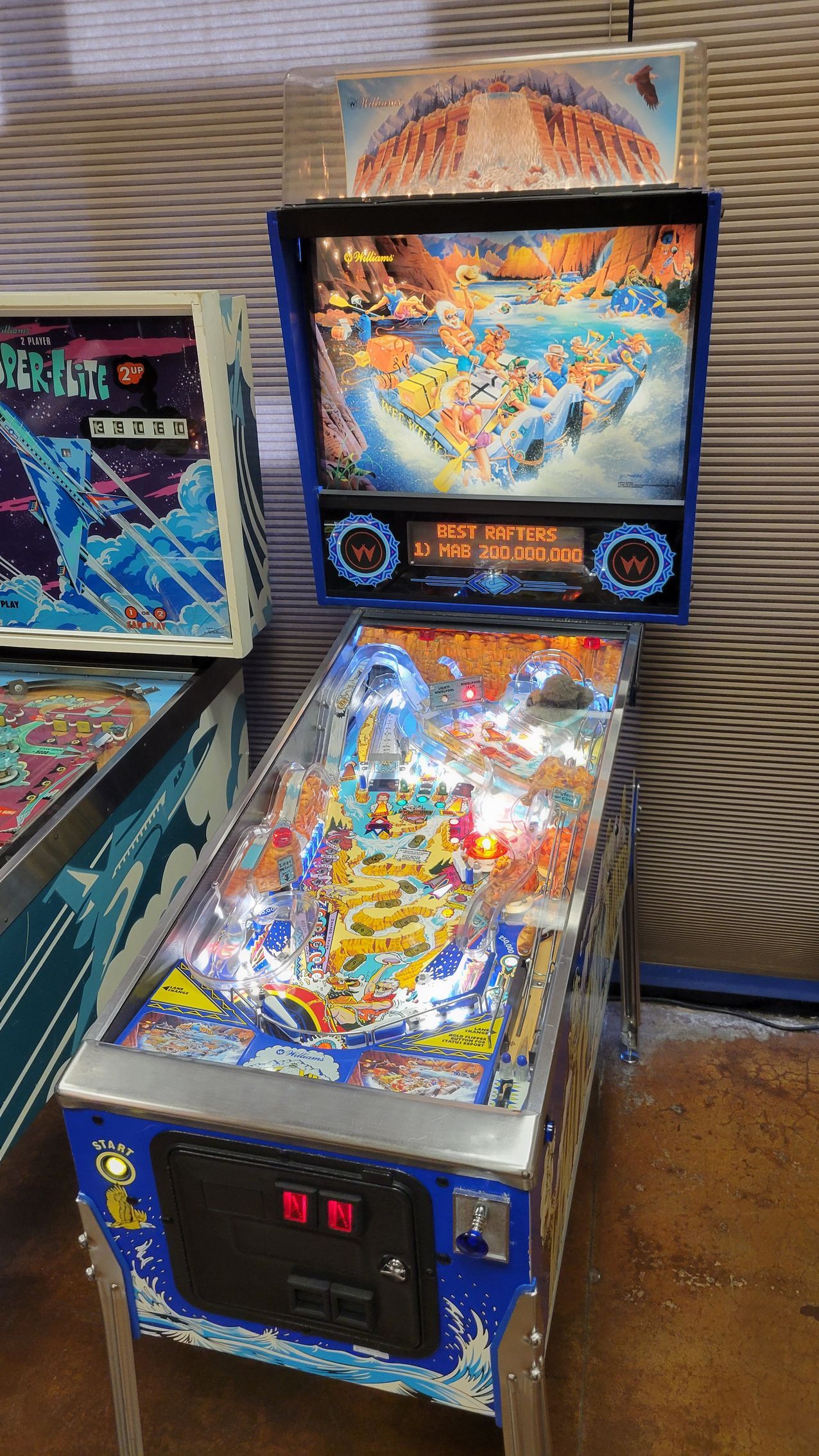 A pinball machine is sitting on a table next to other pinball machines.