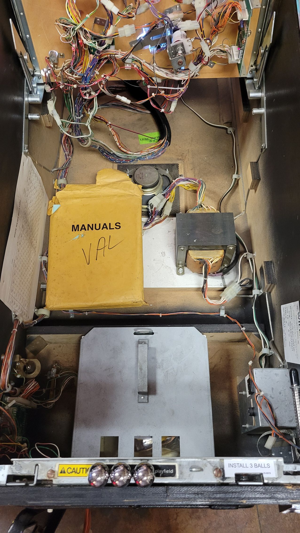 The inside of a pinball machine with a lot of wires coming out of it.
