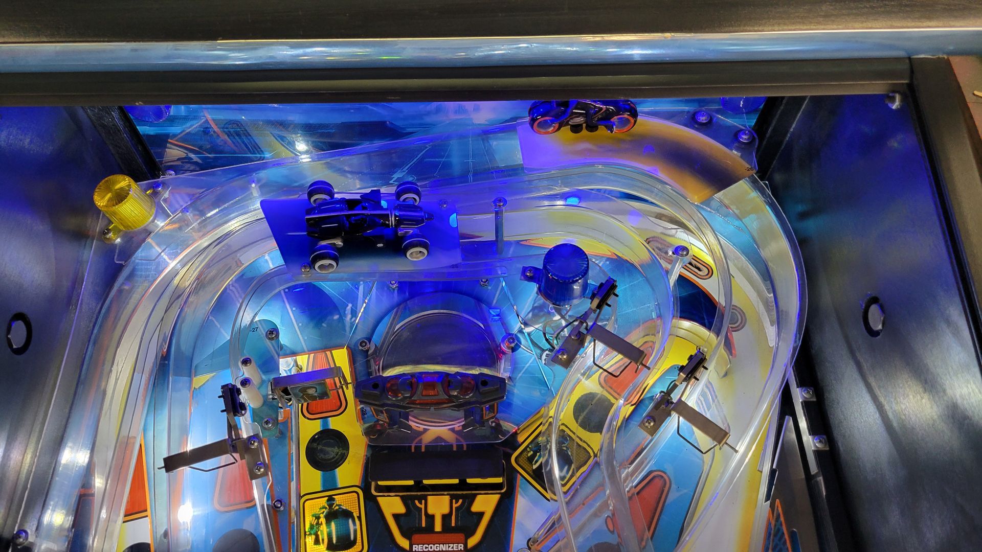 A close up of a pinball machine with cars on it.