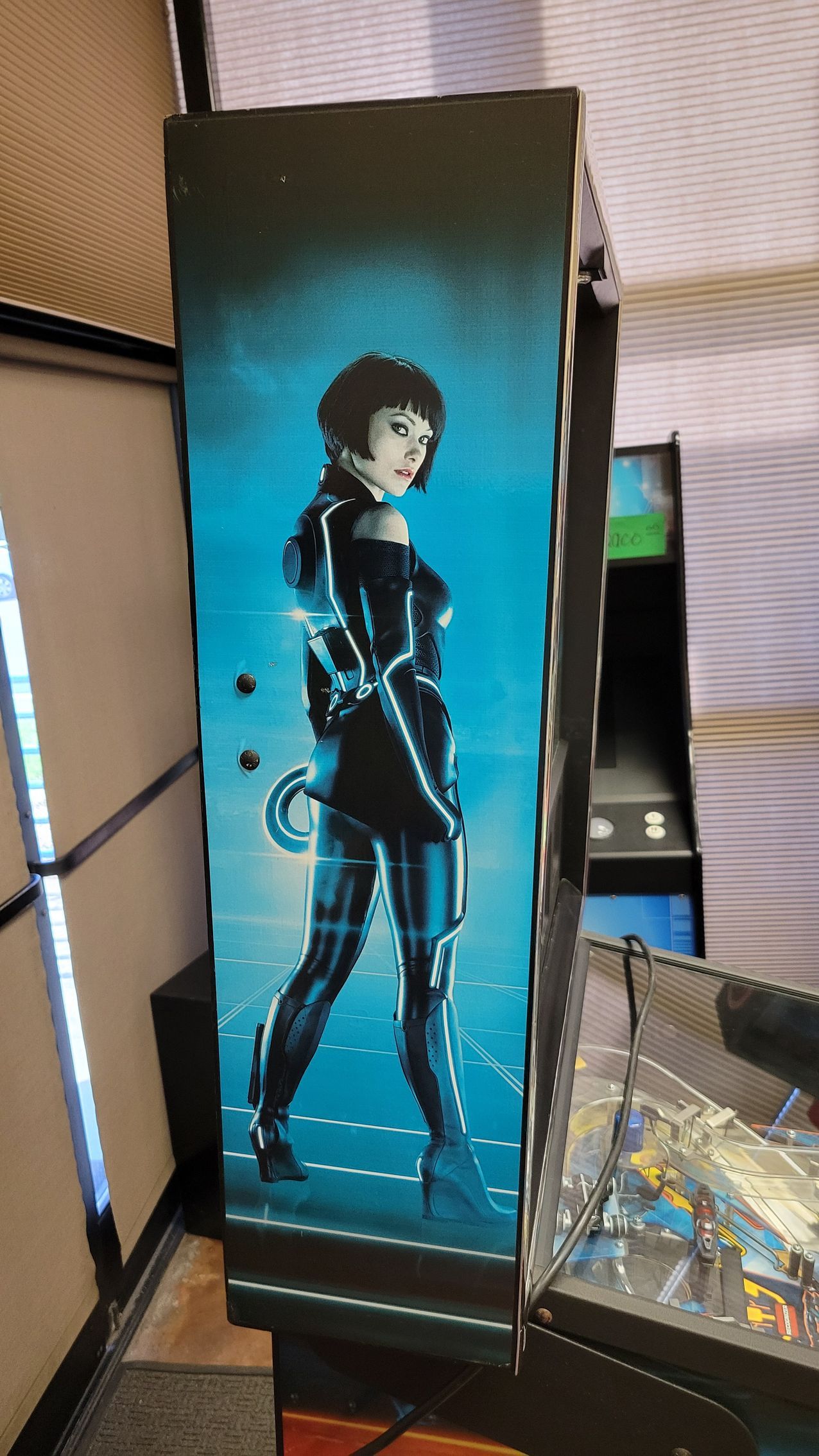 A painting of a woman in a futuristic outfit is on the side of an arcade machine.