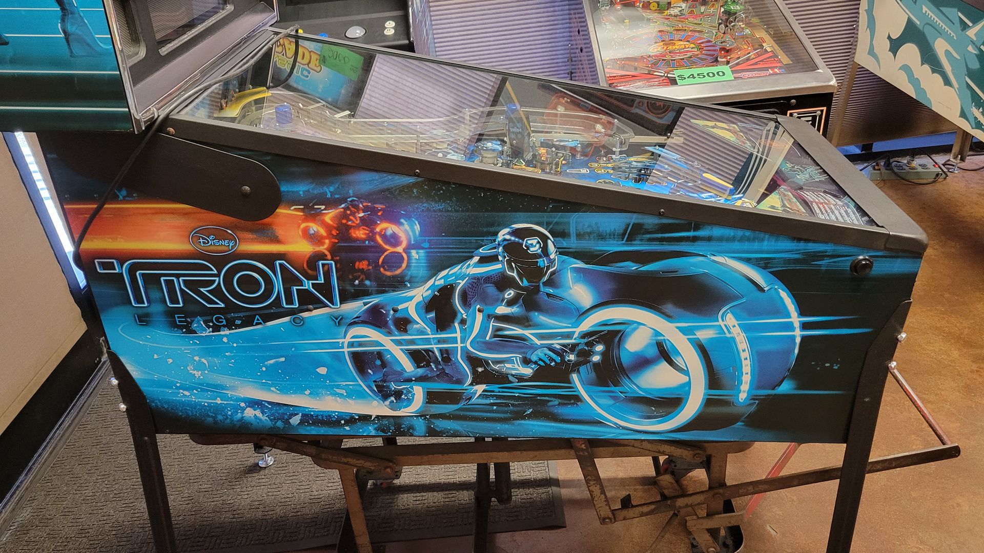 A tron pinball machine is sitting on a wooden table.