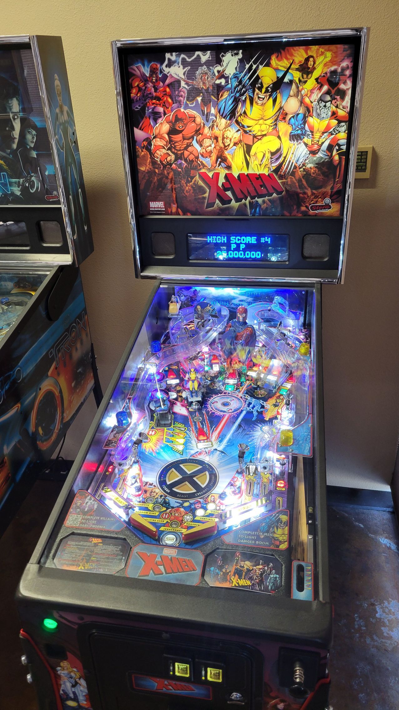 A pinball machine is sitting on a wooden floor in a room.