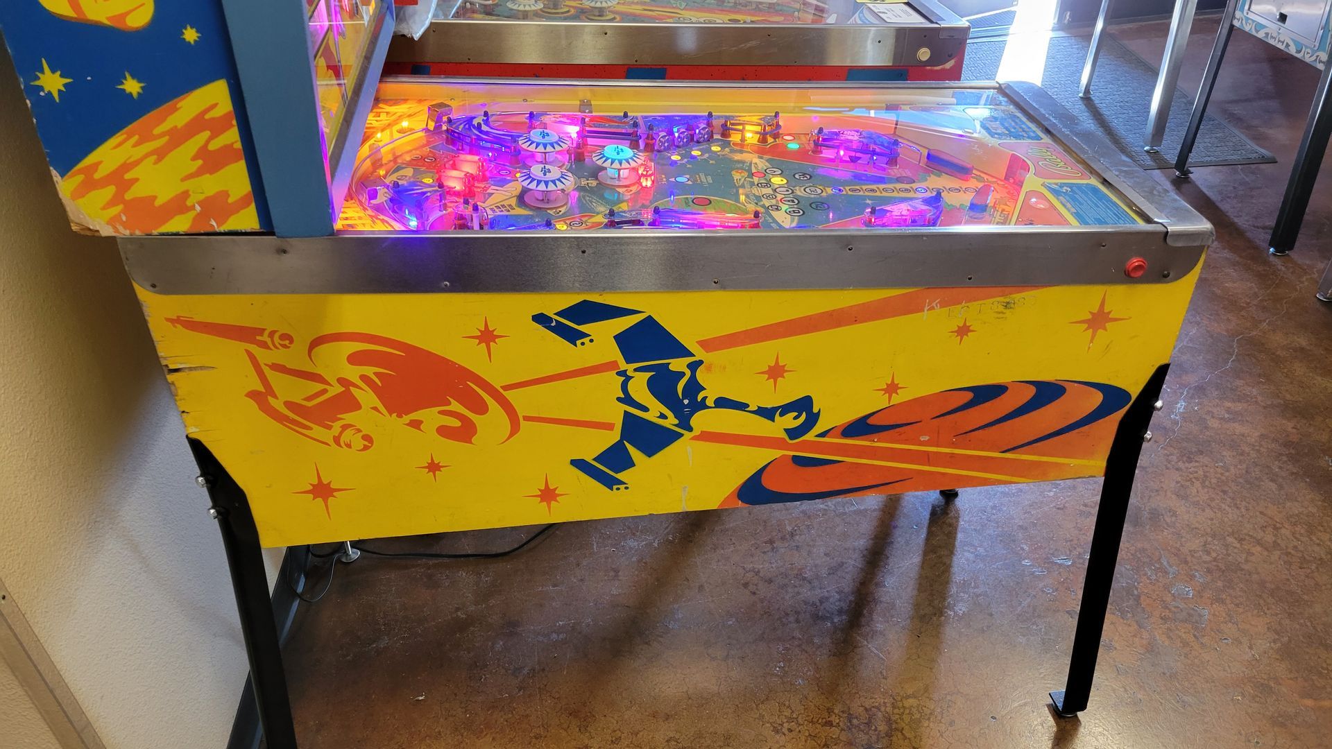 A pinball machine is sitting on the floor in a room.