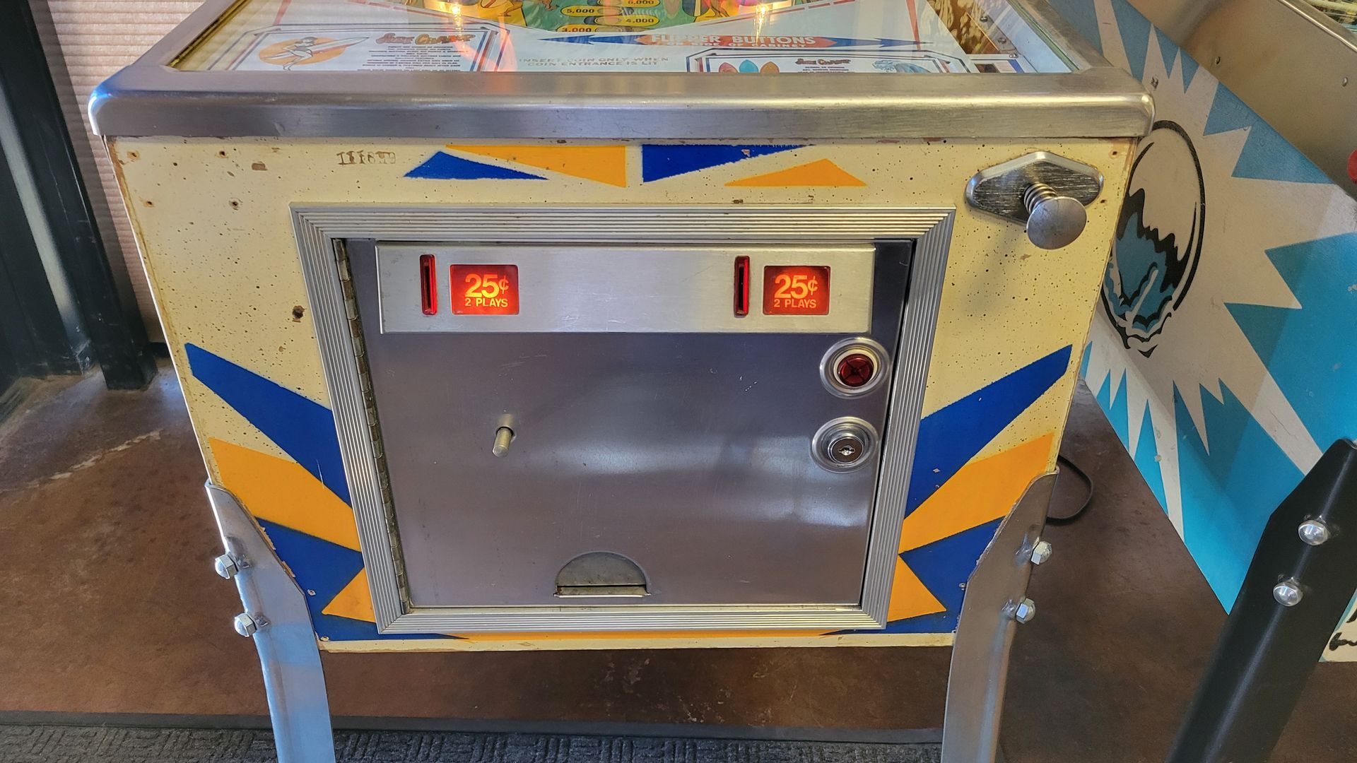 A pinball machine is sitting on the floor with the door open