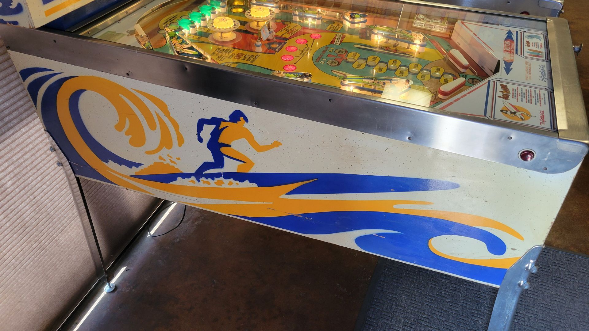 A pinball machine with a surfer on it