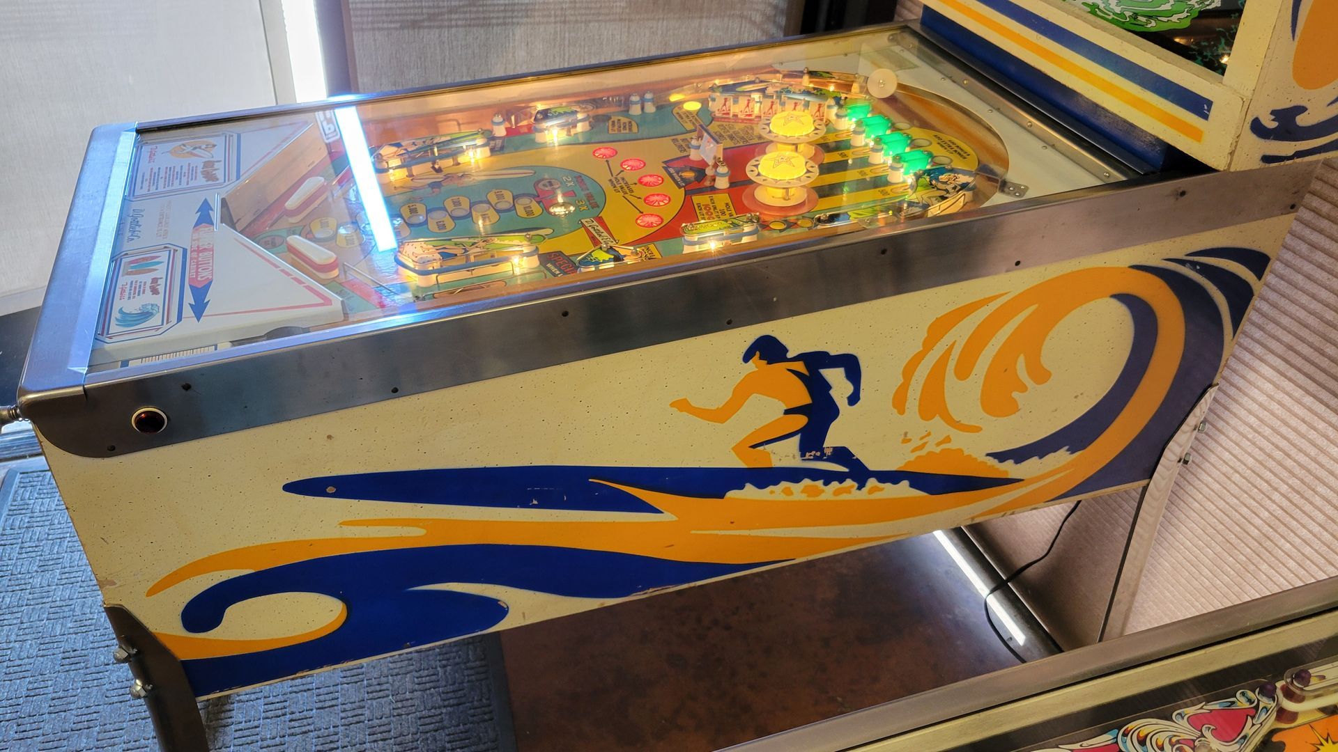 A pinball machine with a surfer on it