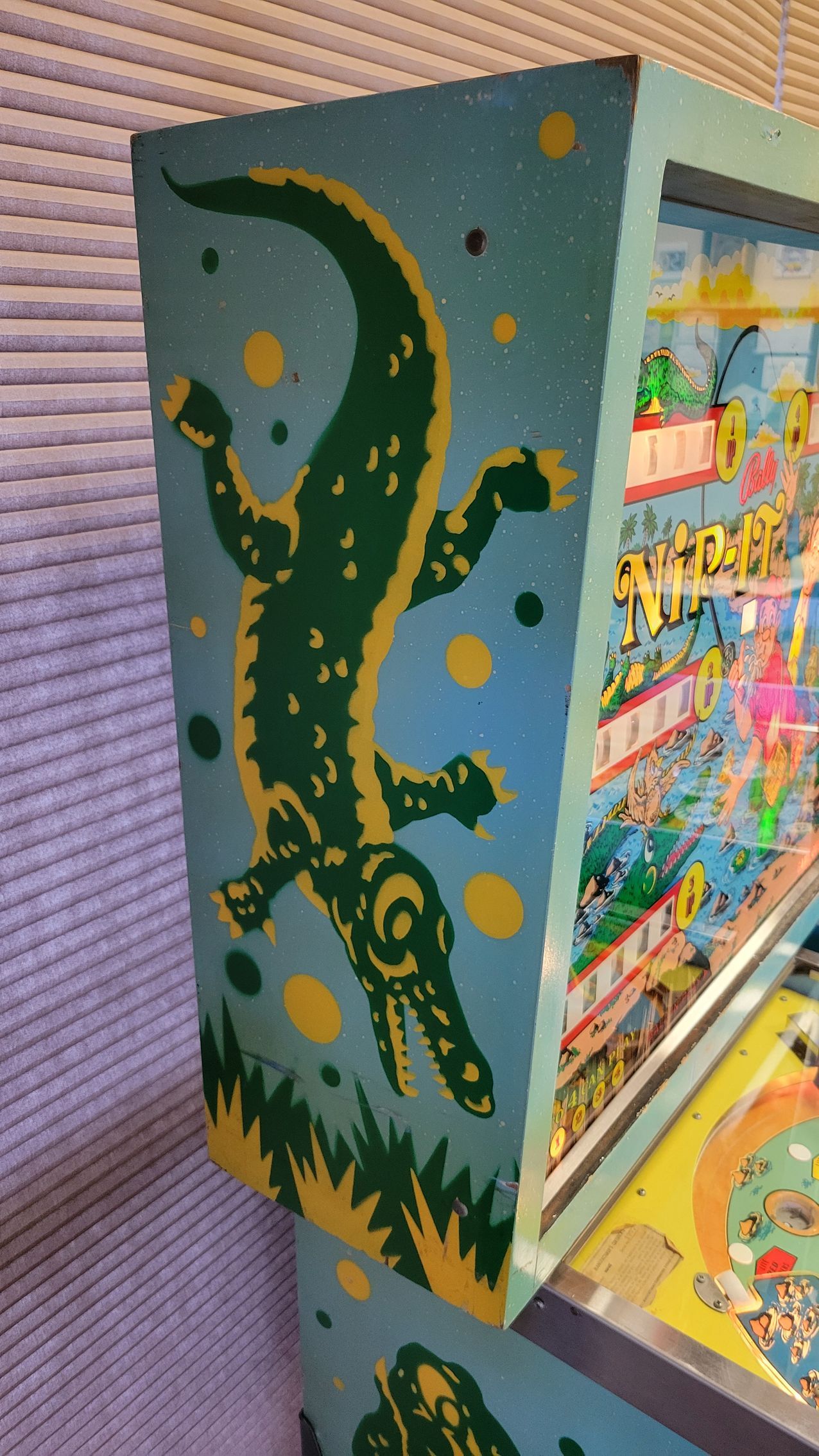 A crocodile is painted on the side of a pinball machine.