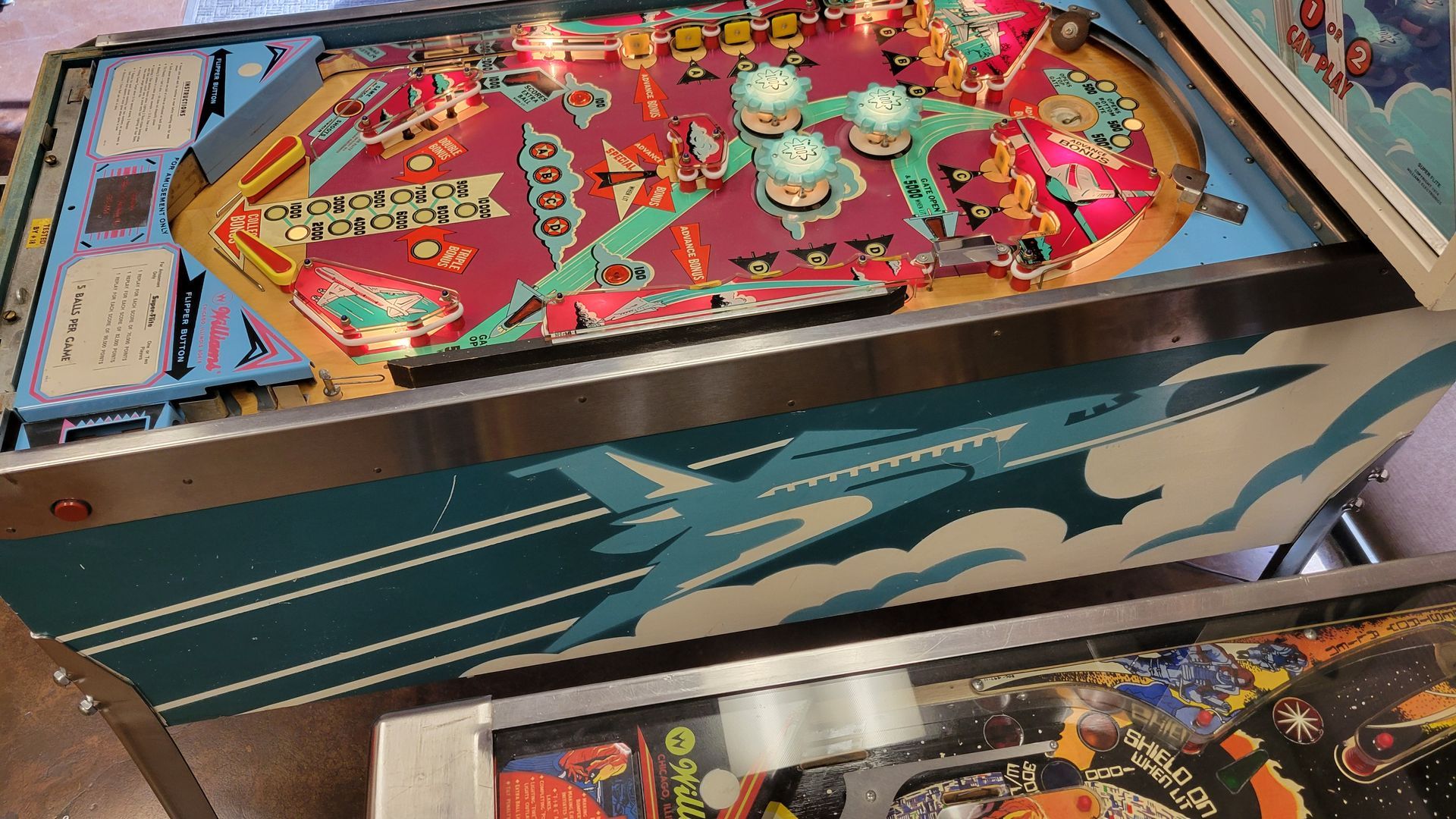 Three pinball machines are lined up on a table.