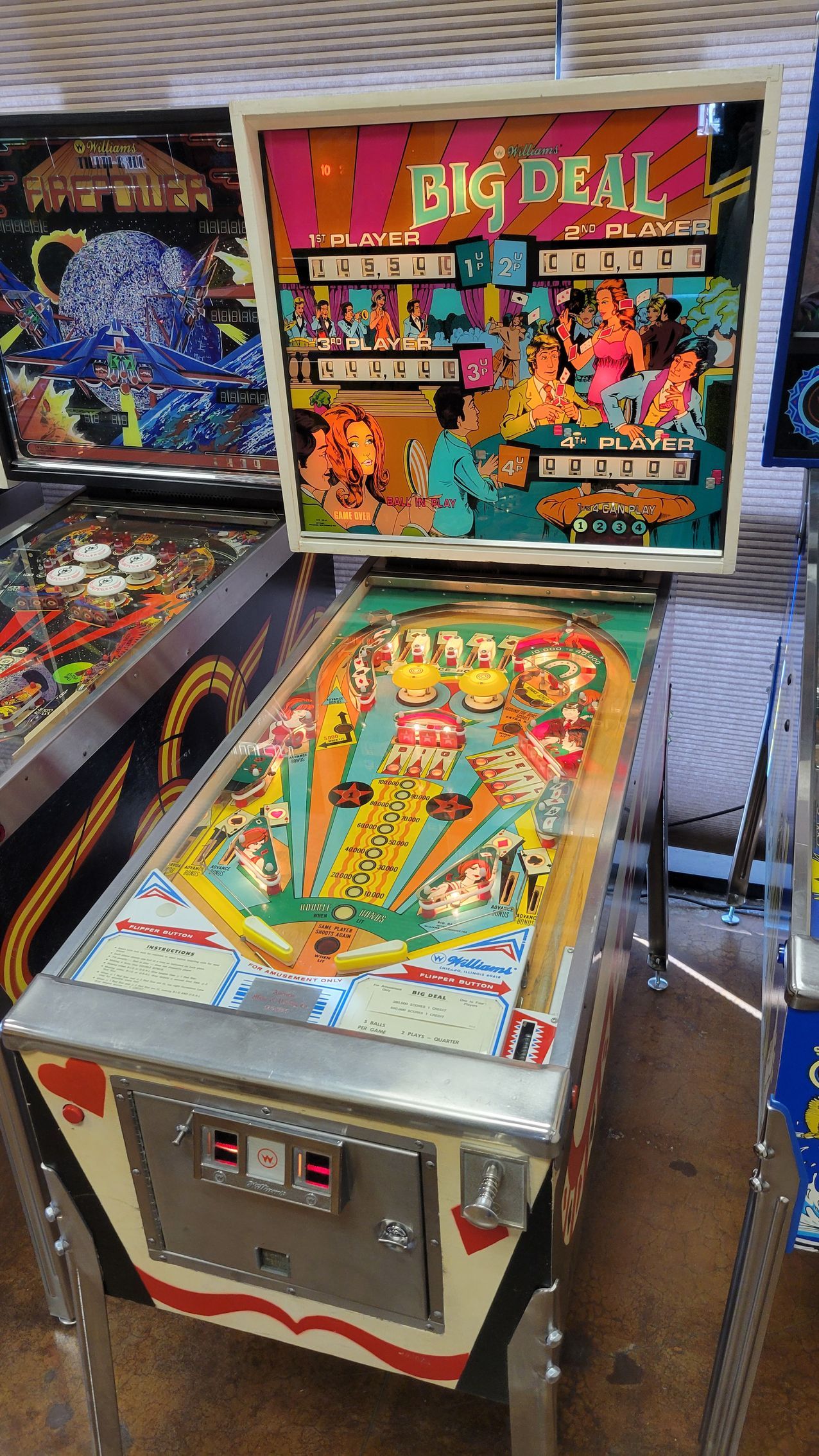 A pinball machine is sitting on a table next to other pinball machines.