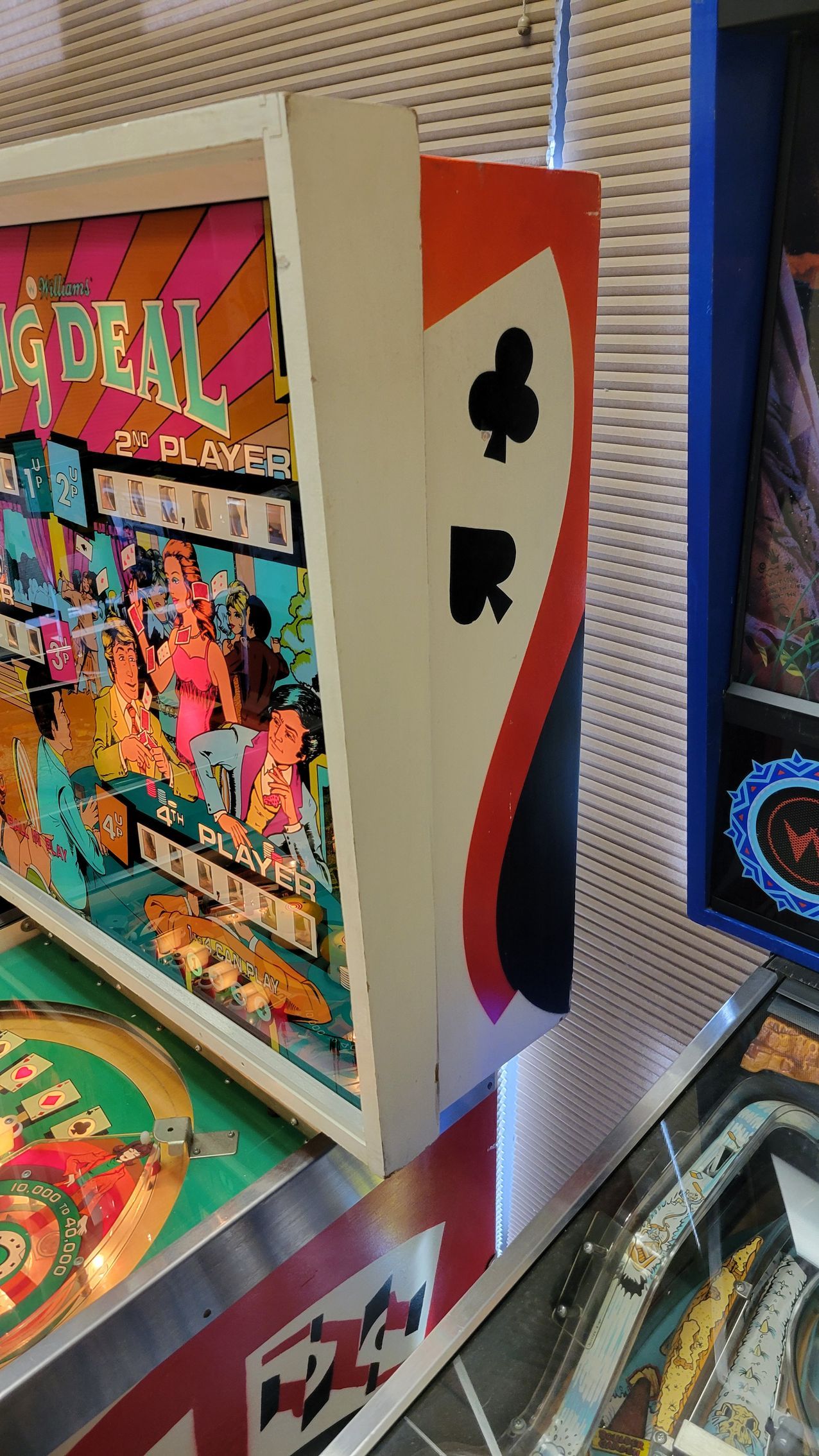 A close up of a pinball machine with playing cards on it.