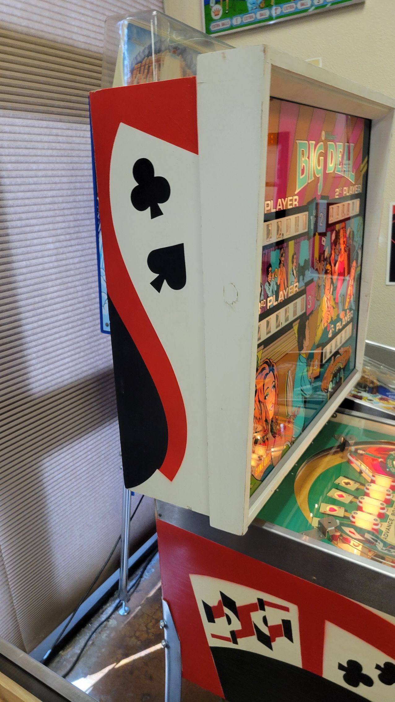 A pinball machine with playing cards on it is sitting on a table.