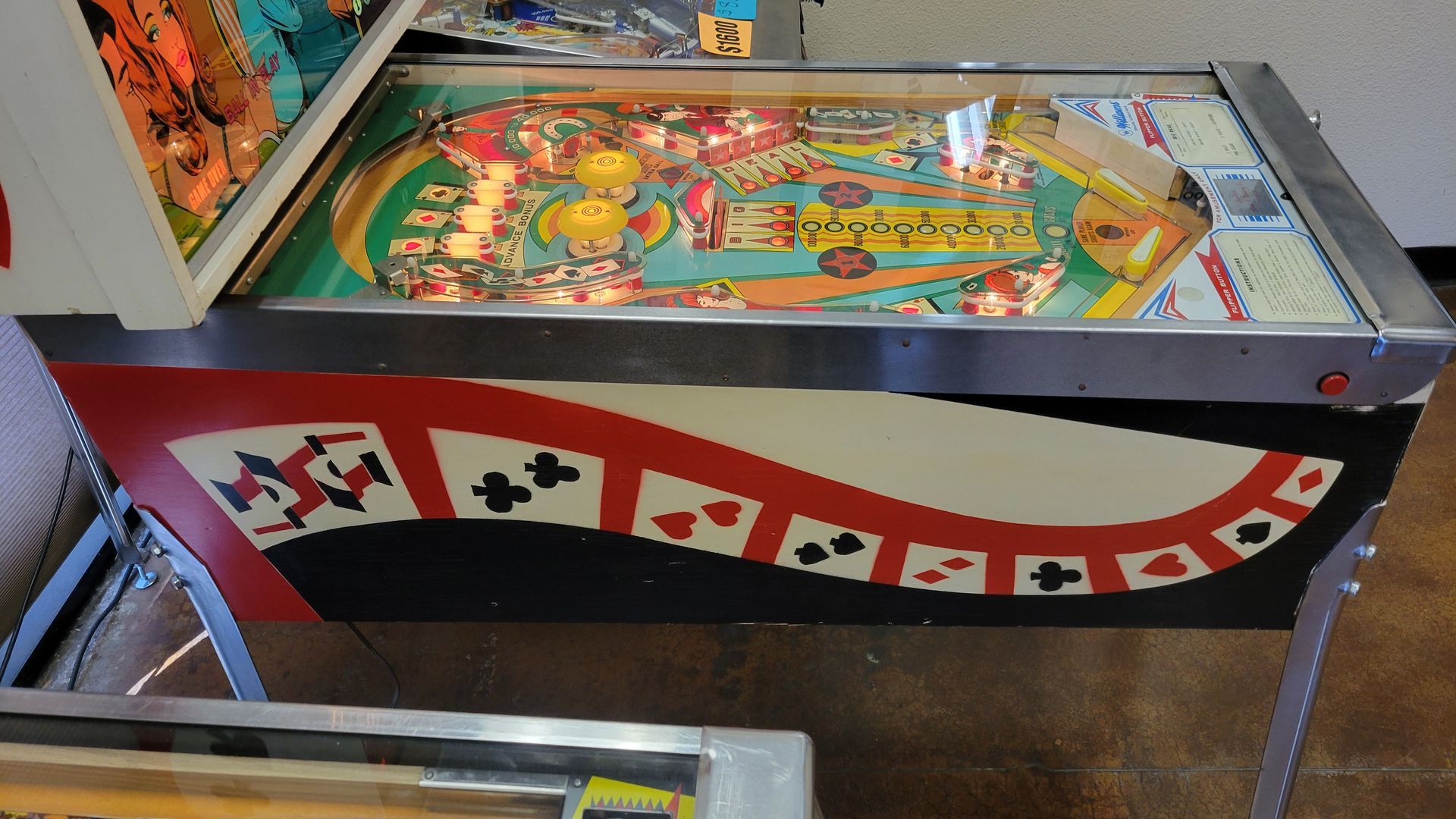 A pinball machine with playing cards on it
