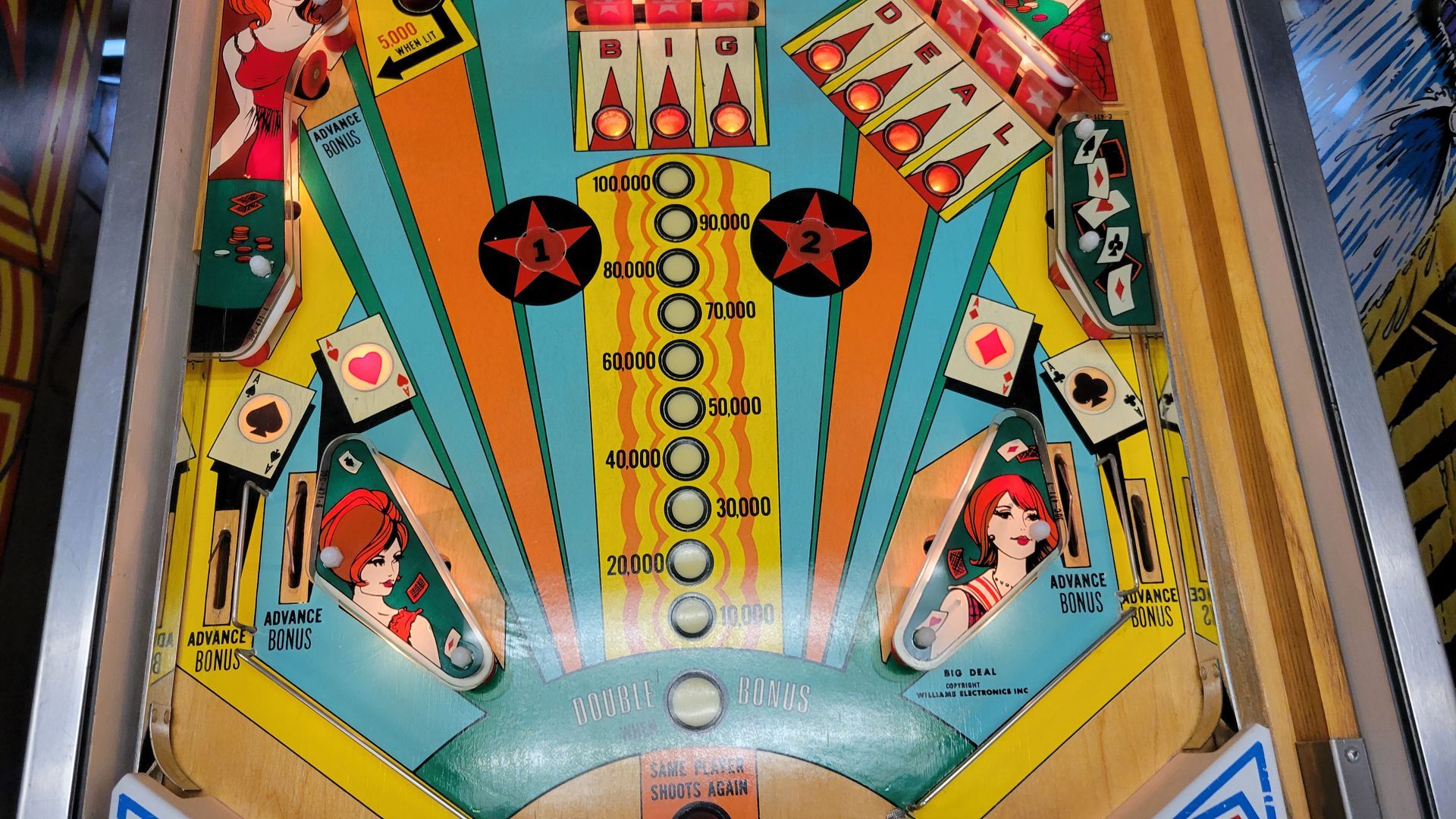 A close up of a pinball machine with cards on it