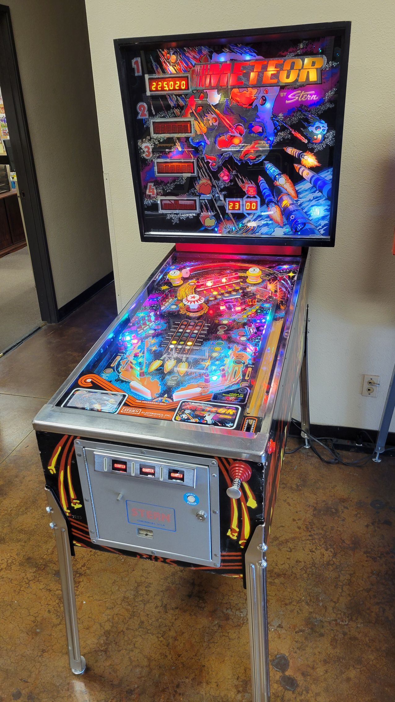 A pinball machine is sitting on a wooden floor in a room.