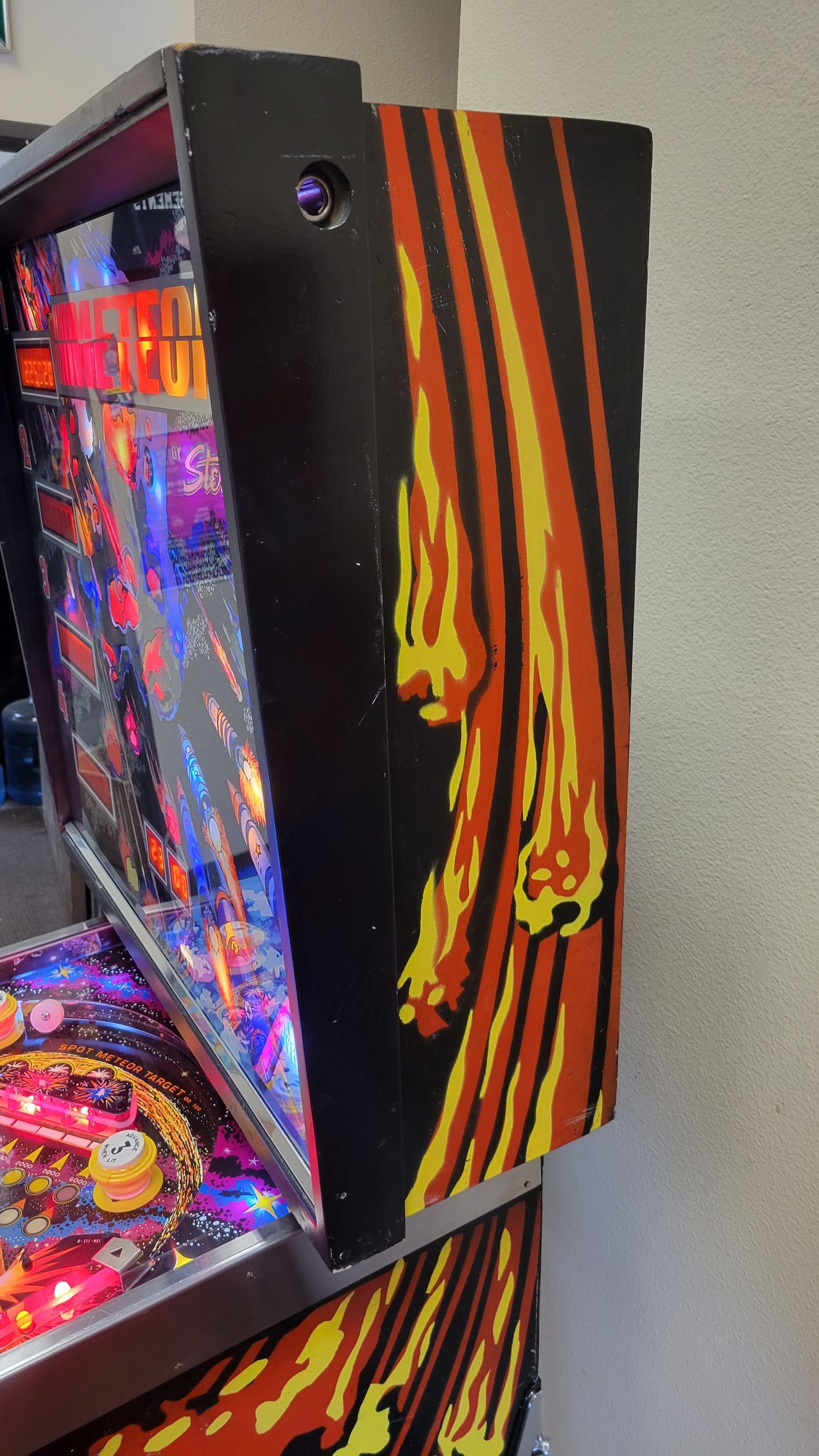 A pinball machine with flames on the side is sitting on a table.