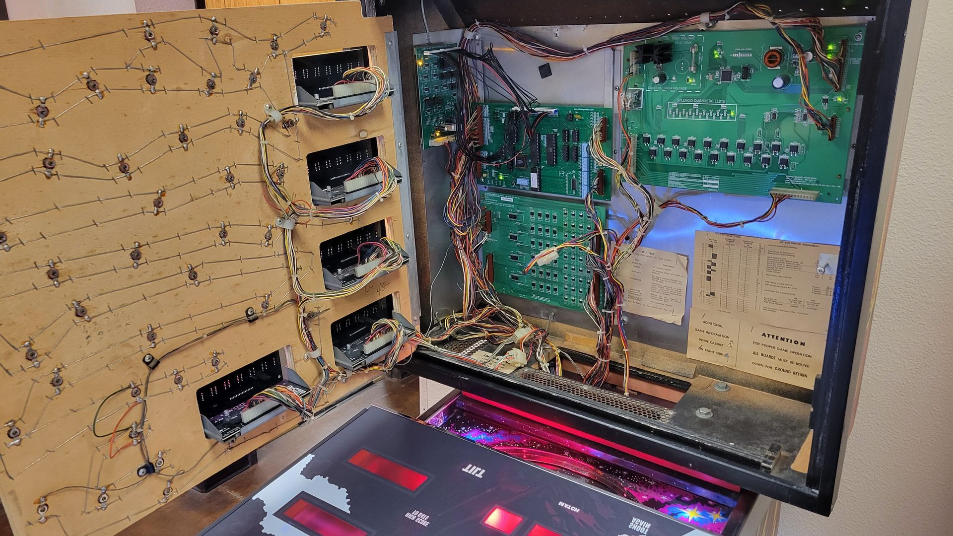 The inside of a pinball machine with a lot of wires coming out of it.