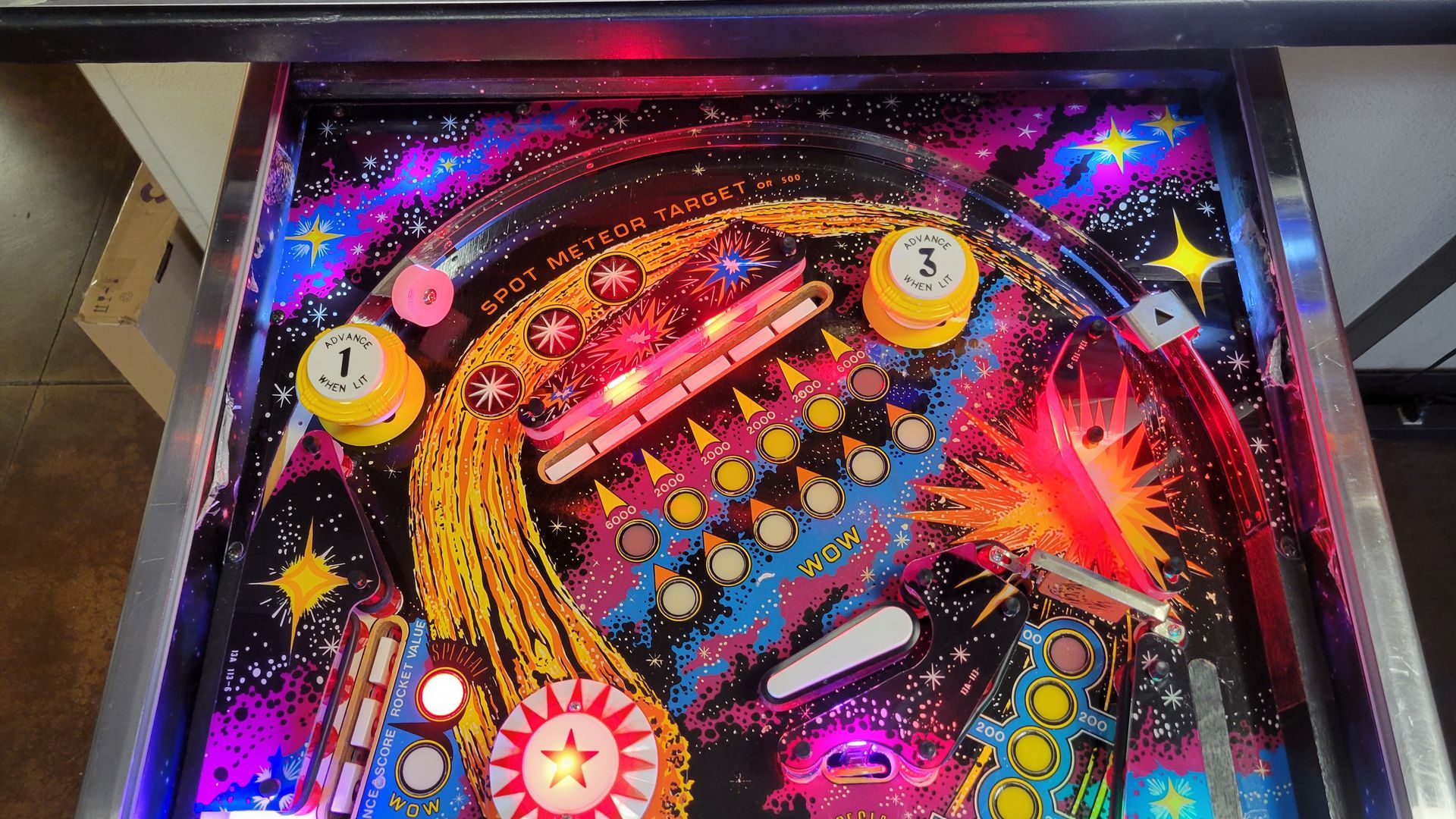 A pinball machine with a galaxy theme is sitting on a table.