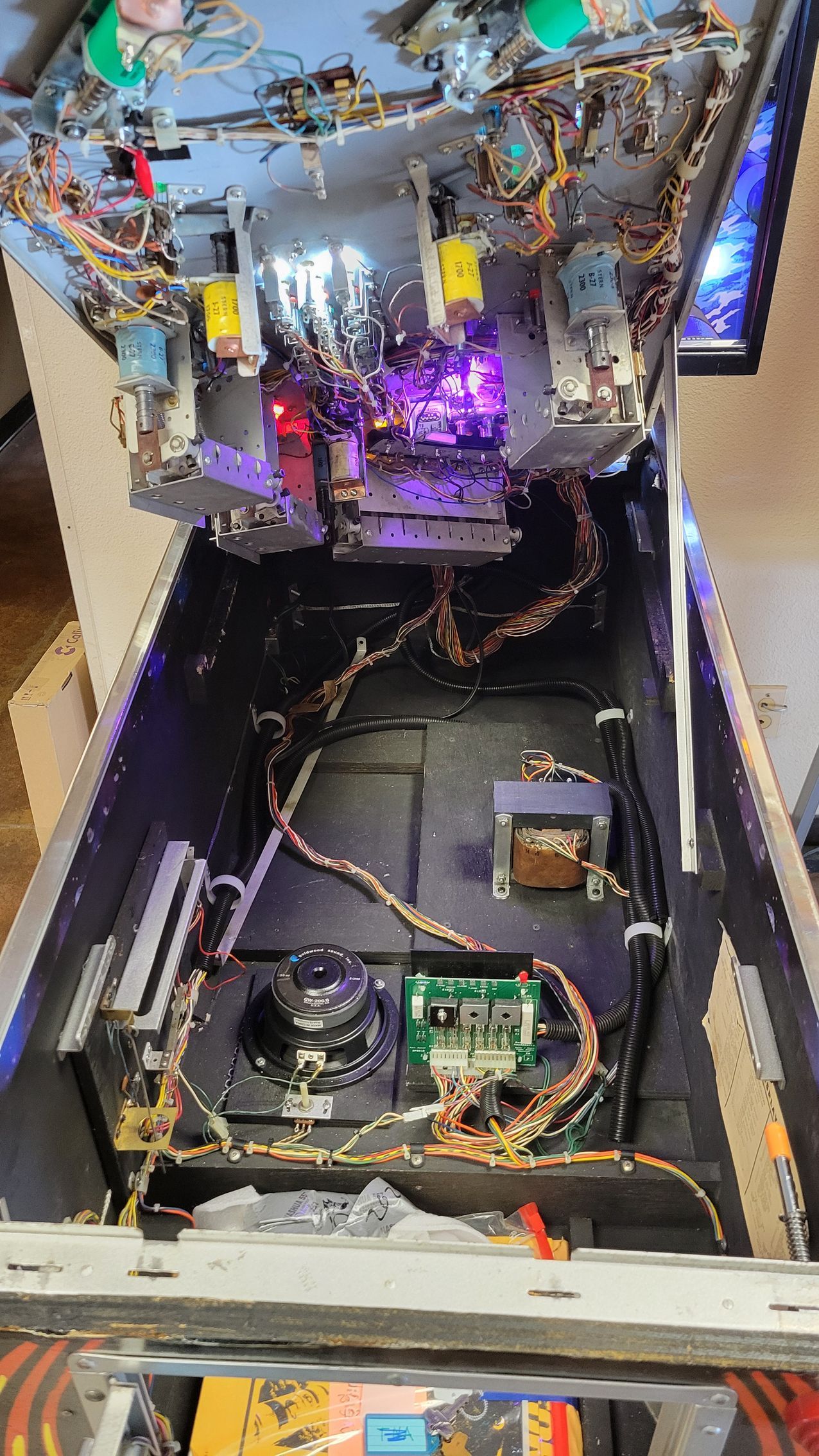 The inside of a pinball machine with a lot of wires coming out of it.