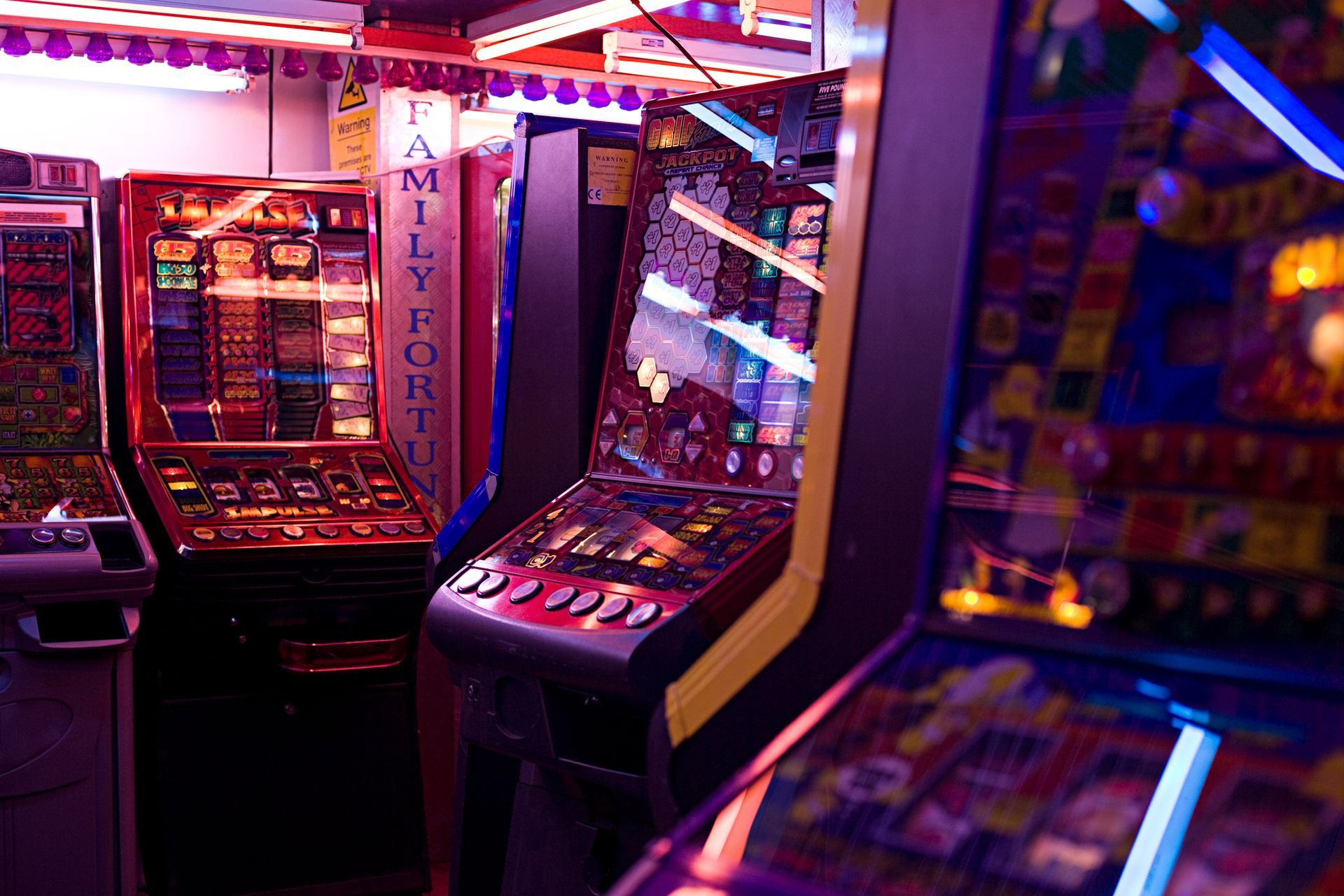 Colorful slot machines and arcade games for sale inside a retro-themed game room.