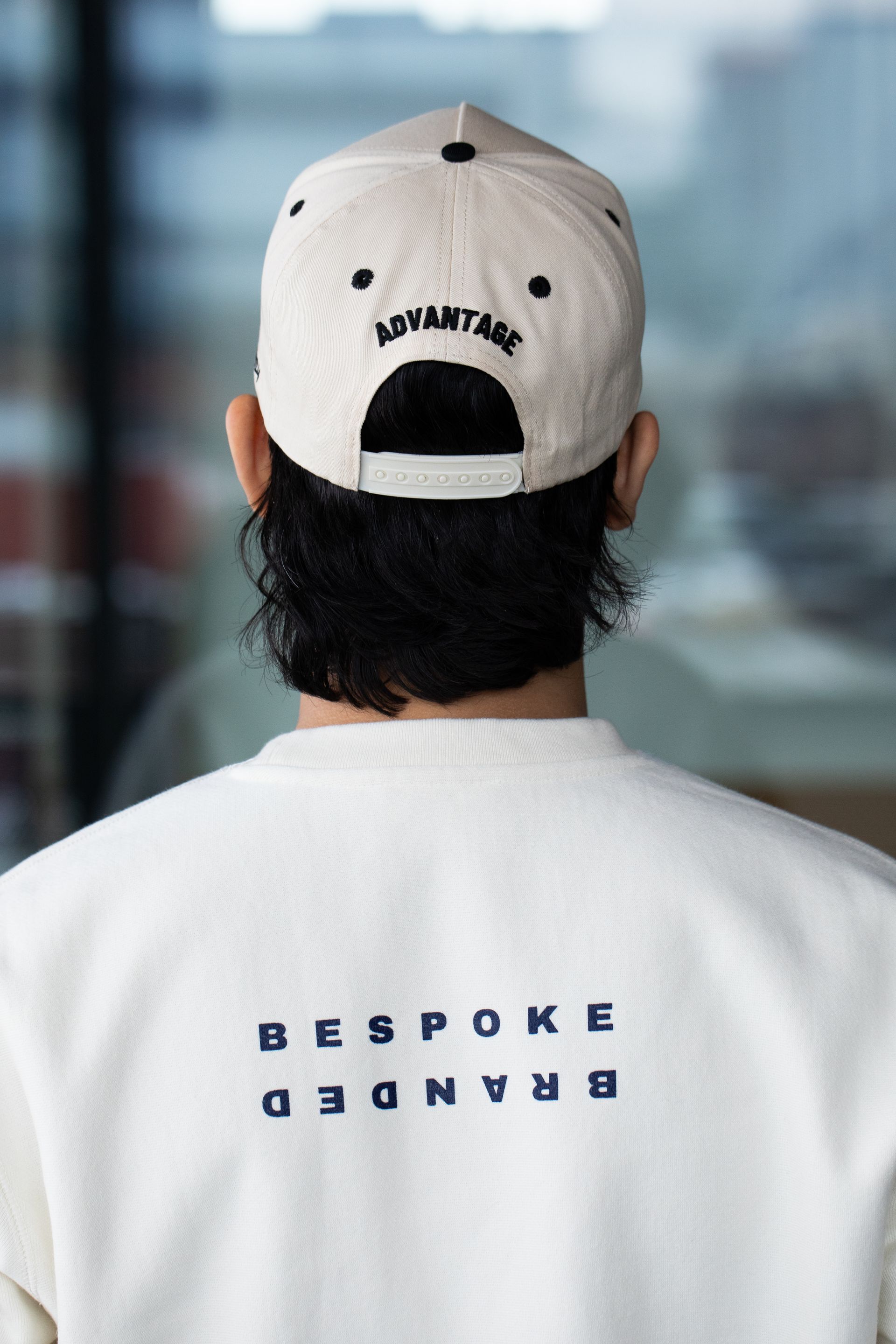 The back of a man wearing a white baseball cap and a white sweatshirt.