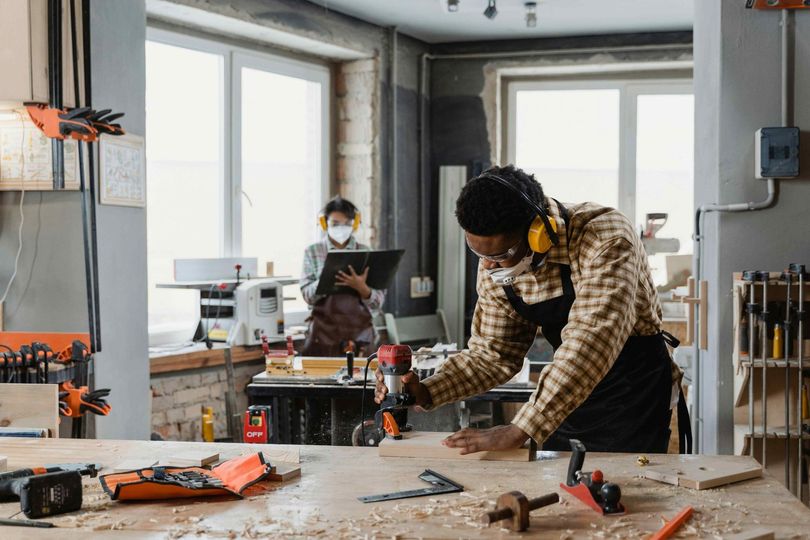 A man is working on a wooden table in a workshop.