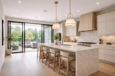 Modern kitchen with a marble waterfall island, light wood cabinetry, and large sliding glass doors leading to a patio.