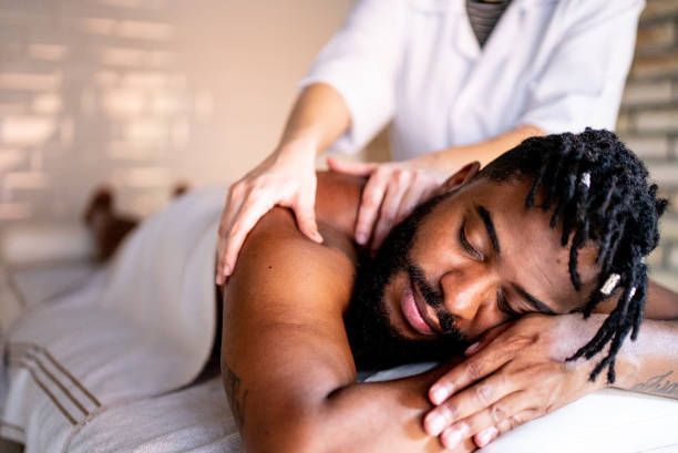 A man is laying on a table getting a massage from a woman.