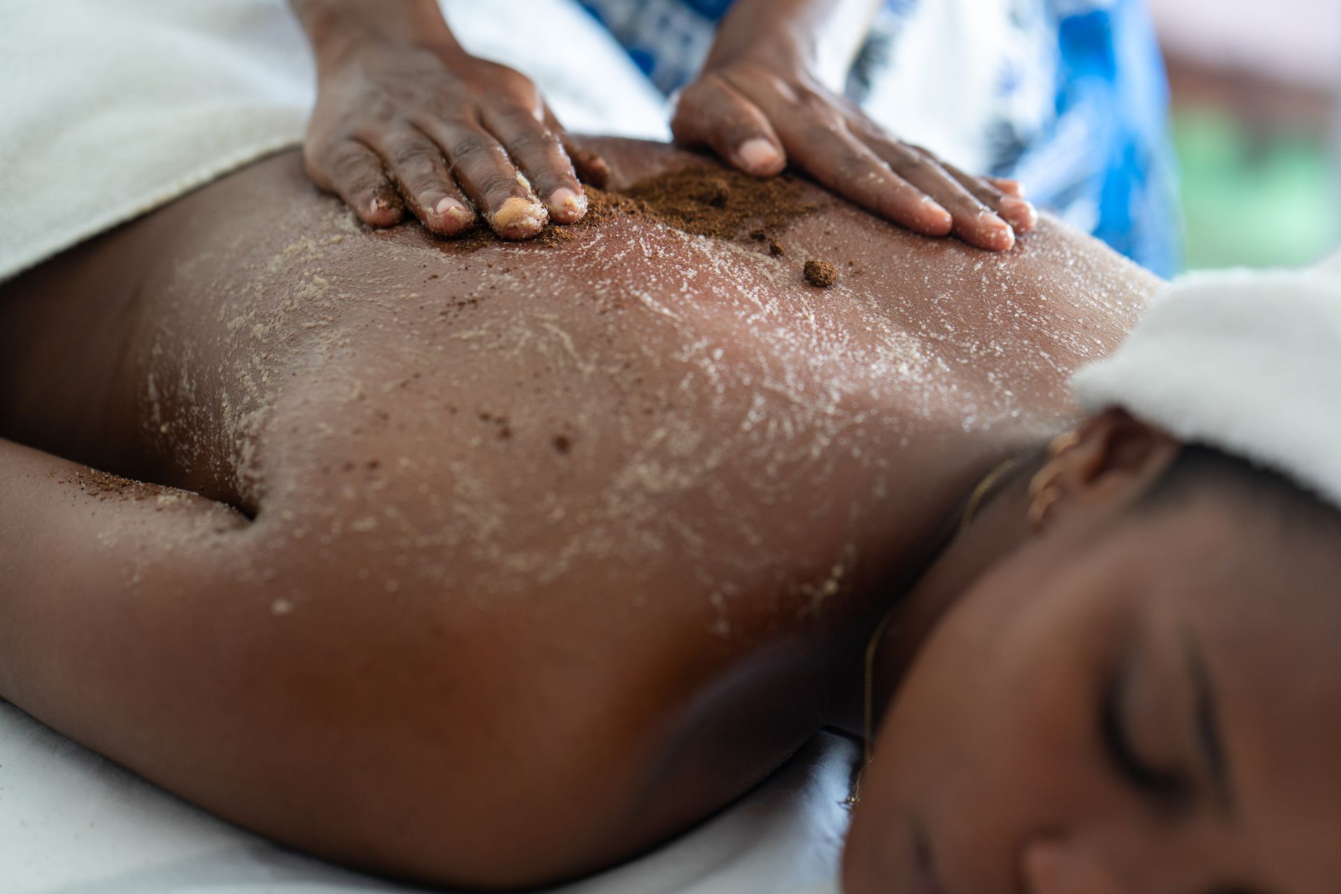 A woman is laying on a bed getting a massage.