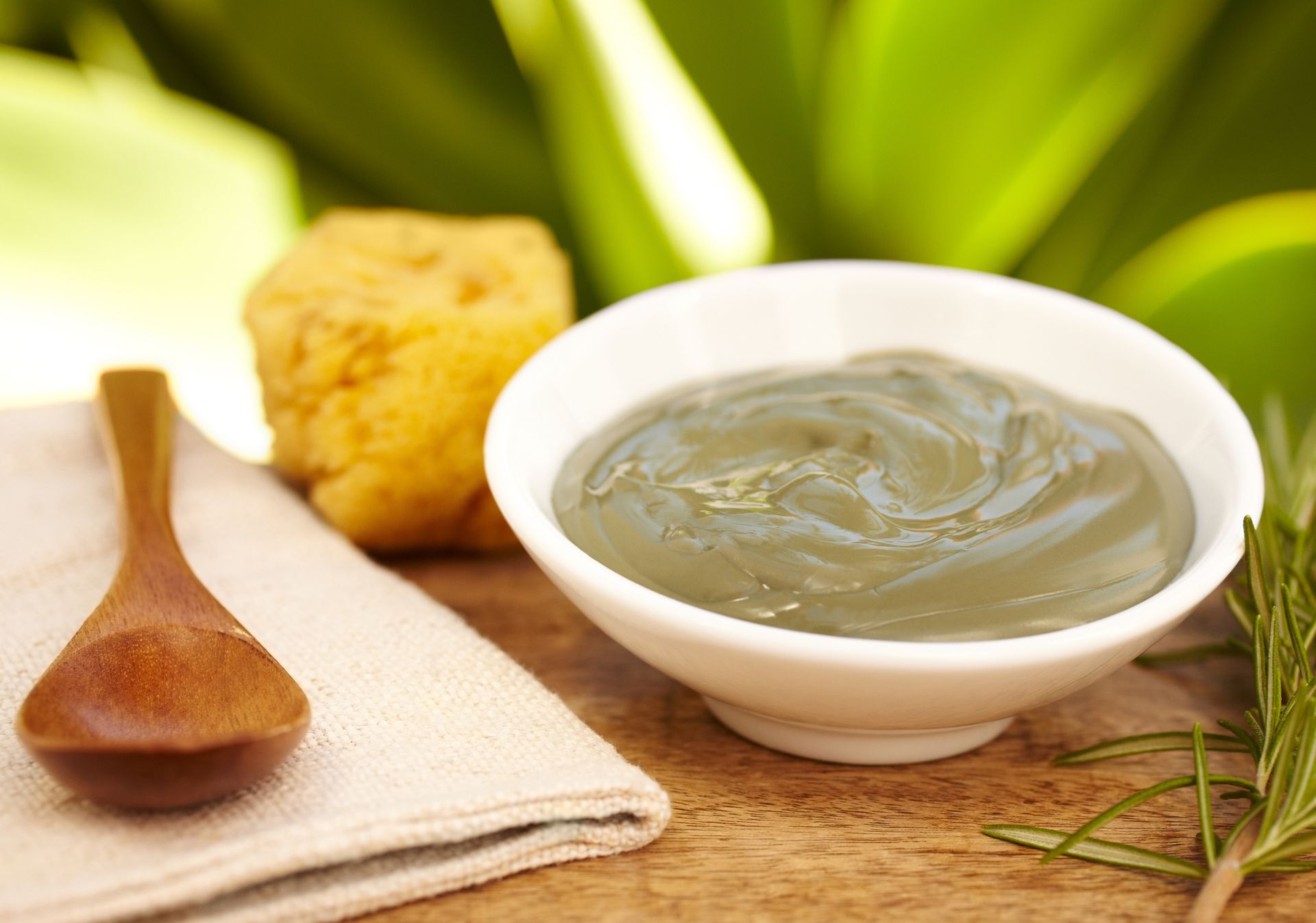 A bowl of clay next to a wooden spoon on a table.
