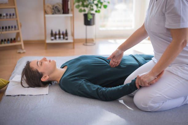 A woman is laying on the floor getting a massage.