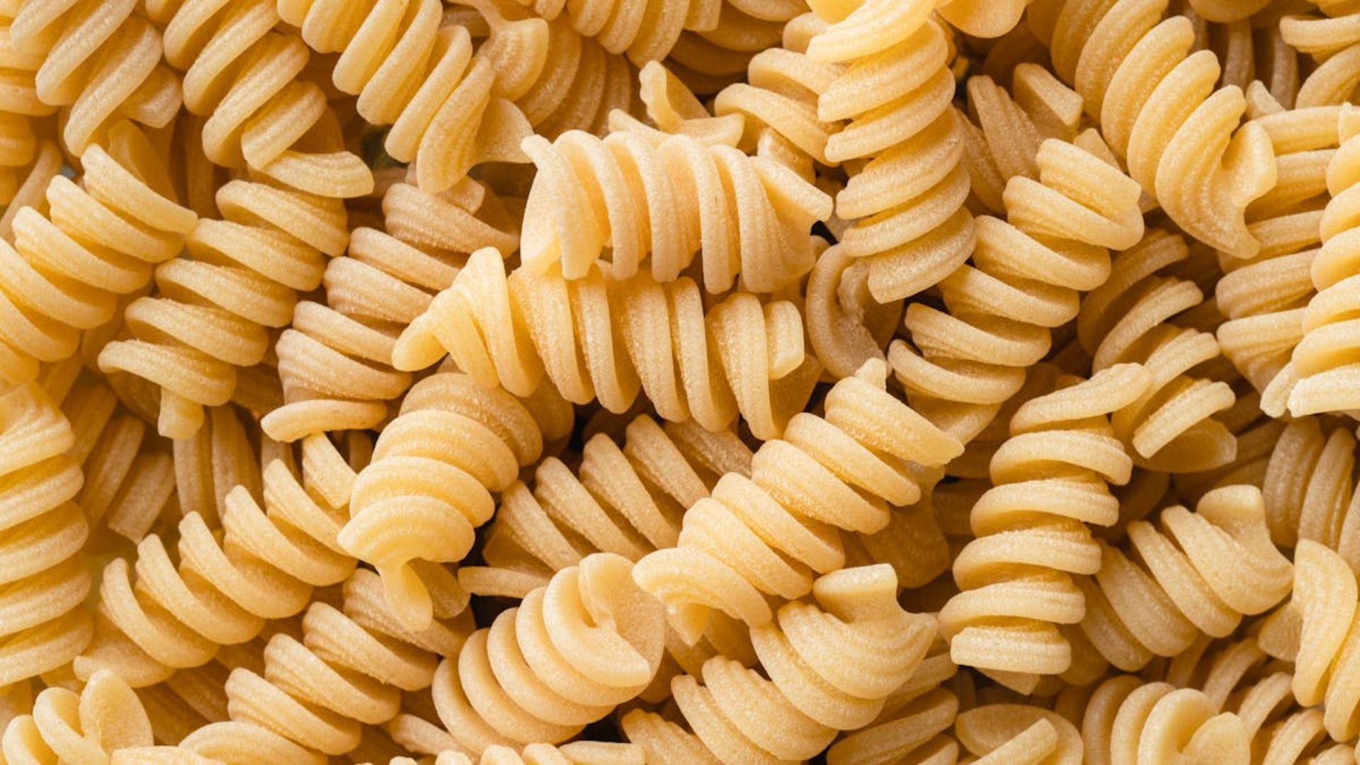 Primer plano de pasta fusilli cruda, que muestra formas espirales y un color amarillo claro.
