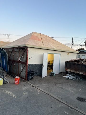 A weathered, white building with a peaked roof.