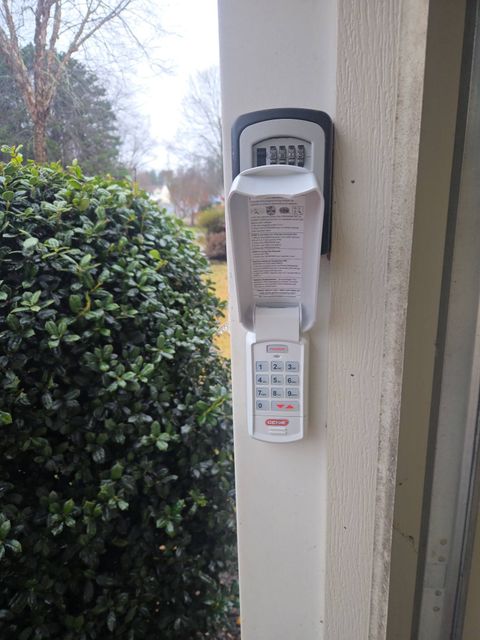 Outdoor wall-mounted keypad intercom with keypad and speaker beside a house entrance