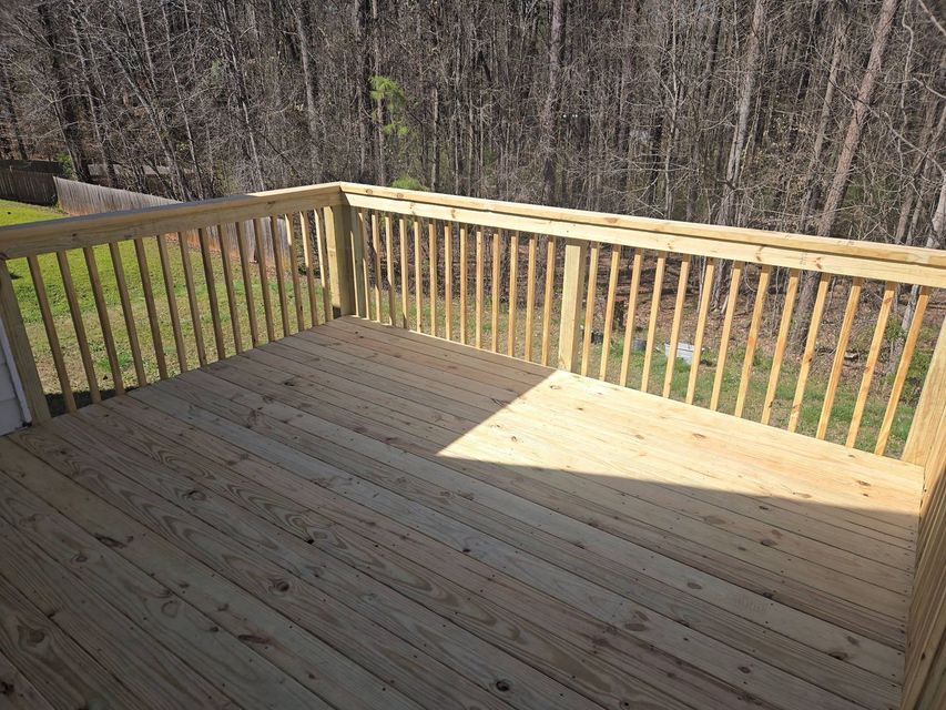 Wooden backyard deck with railings and a sunlit corner overlooking trees