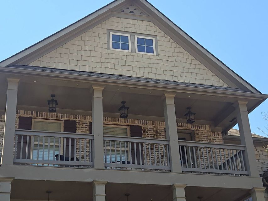 Front porch of a beige house with white railings and columns under a peaked roof