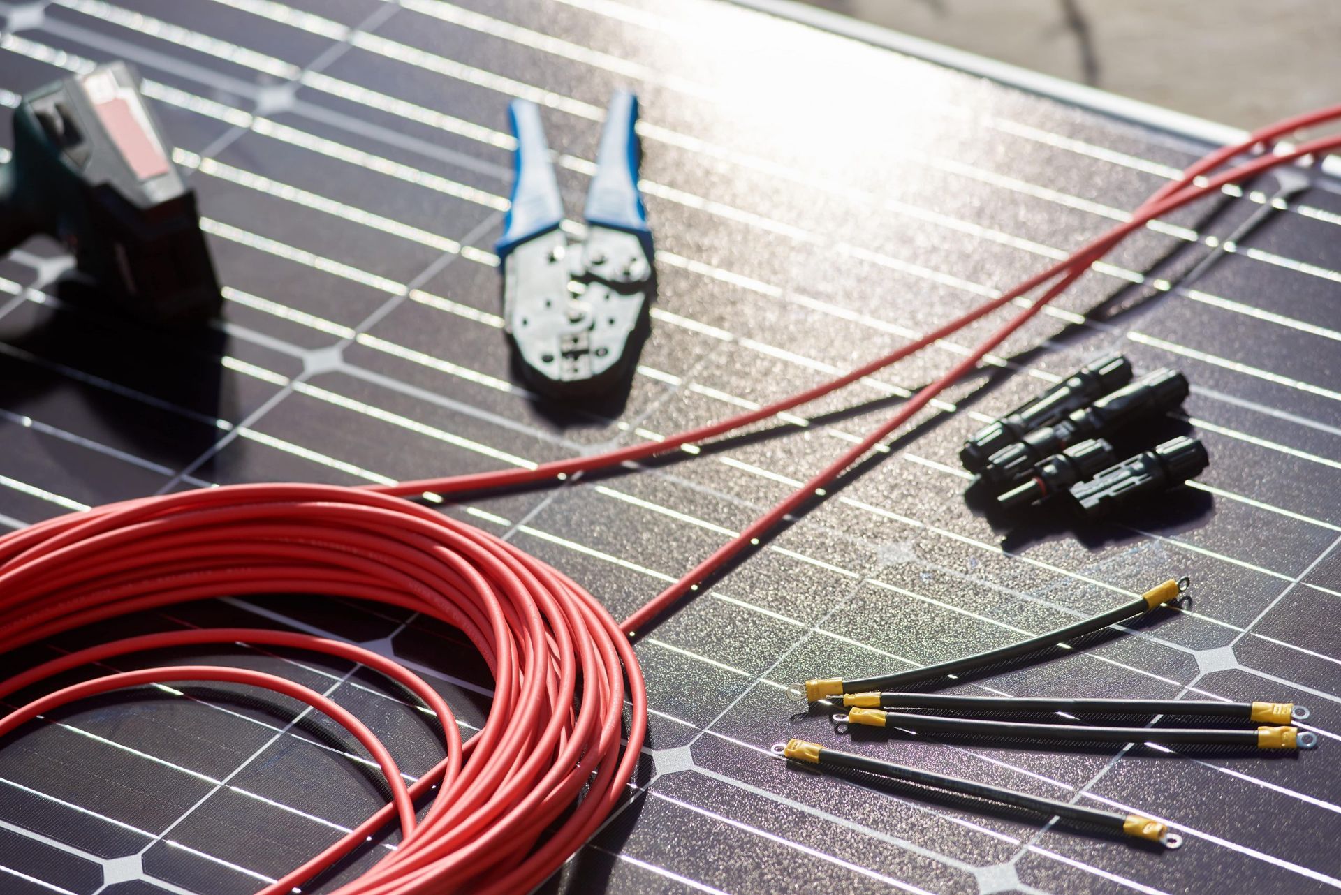 Coiled red solar cables, connectors, and a multimeter on a solar panel surface Coiled red solar cables, connectors, and a multimeter on a solar panel surface