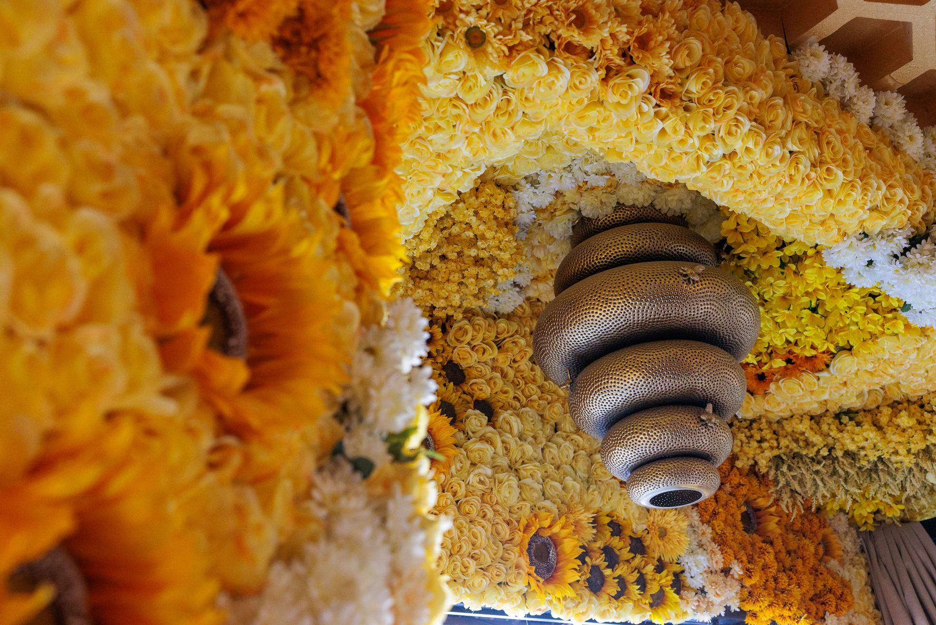 Floral decoration with sunflowers, honeycomb and a decorative bee hive. Yellow, gold, and white hues.