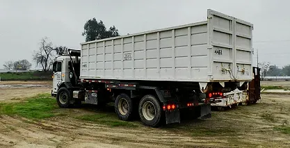 A white dump truck on a dirt road for waste disposal