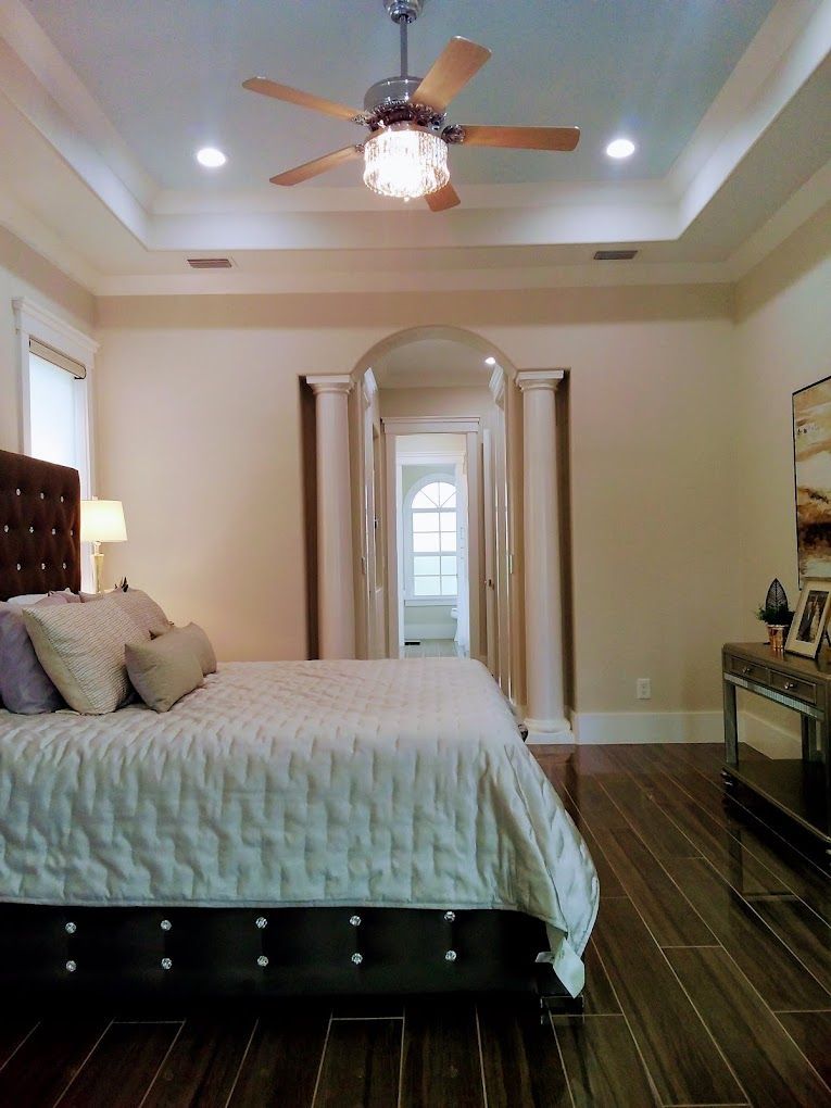 luxury bedroom with ceiling fan, abundant lighting, and shiny wood design flooring
