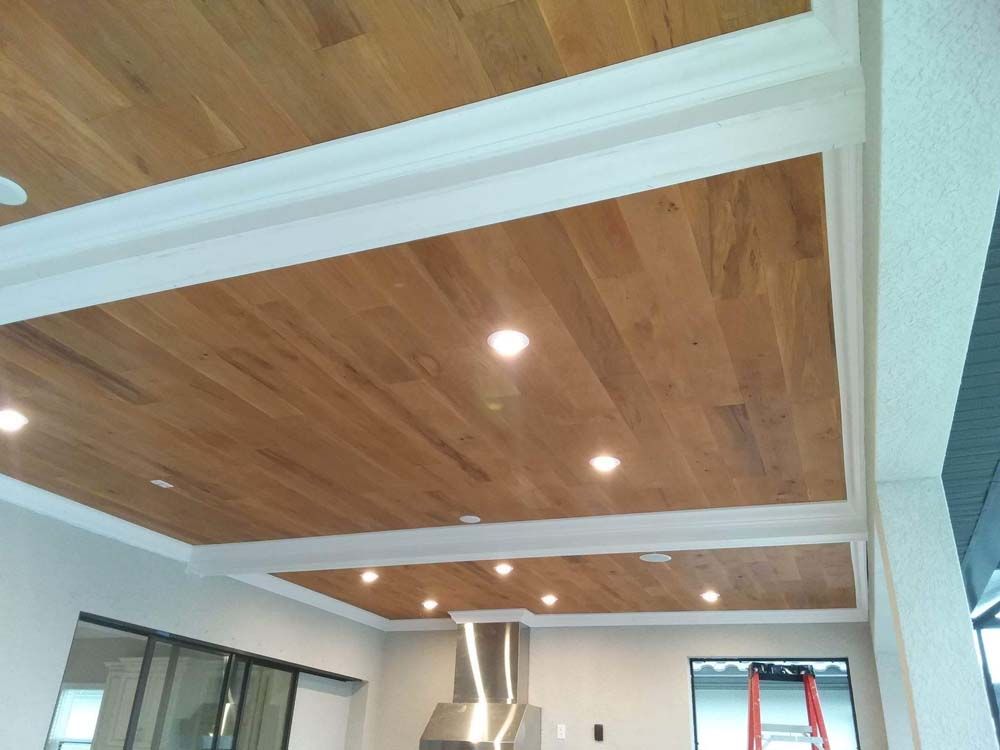 Wooden plank ceiling with white trim and recessed lights.