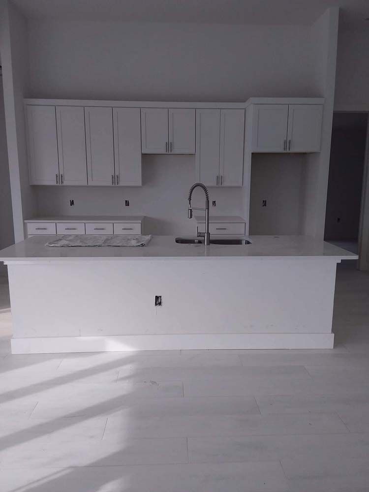 White kitchen with cabinets, countertop, and sink, under construction.