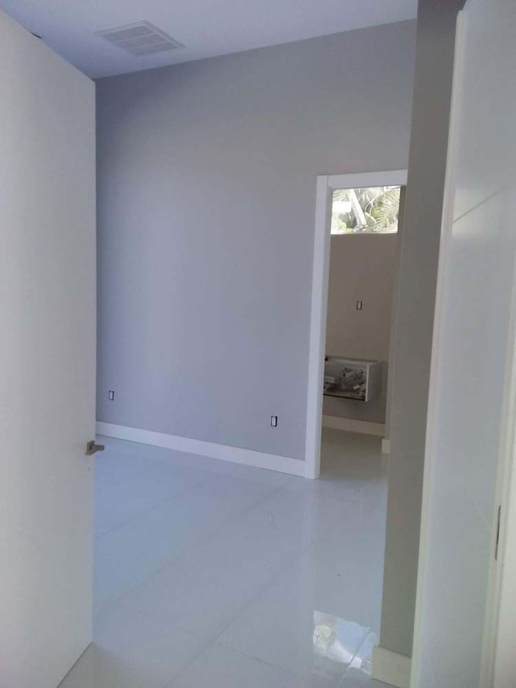 Empty room with gray walls, white trim, and a tiled floor. Doorways lead to other rooms.