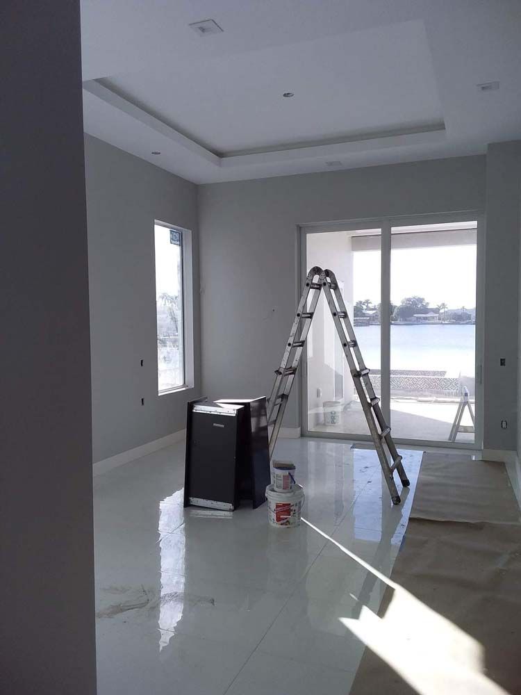 Interior room with ladder, paint, and black appliance. Large window overlooks water.