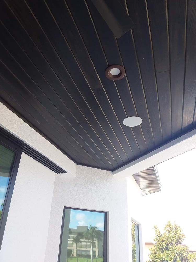 Dark wooden slatted ceiling with recessed lights over a white stucco patio.