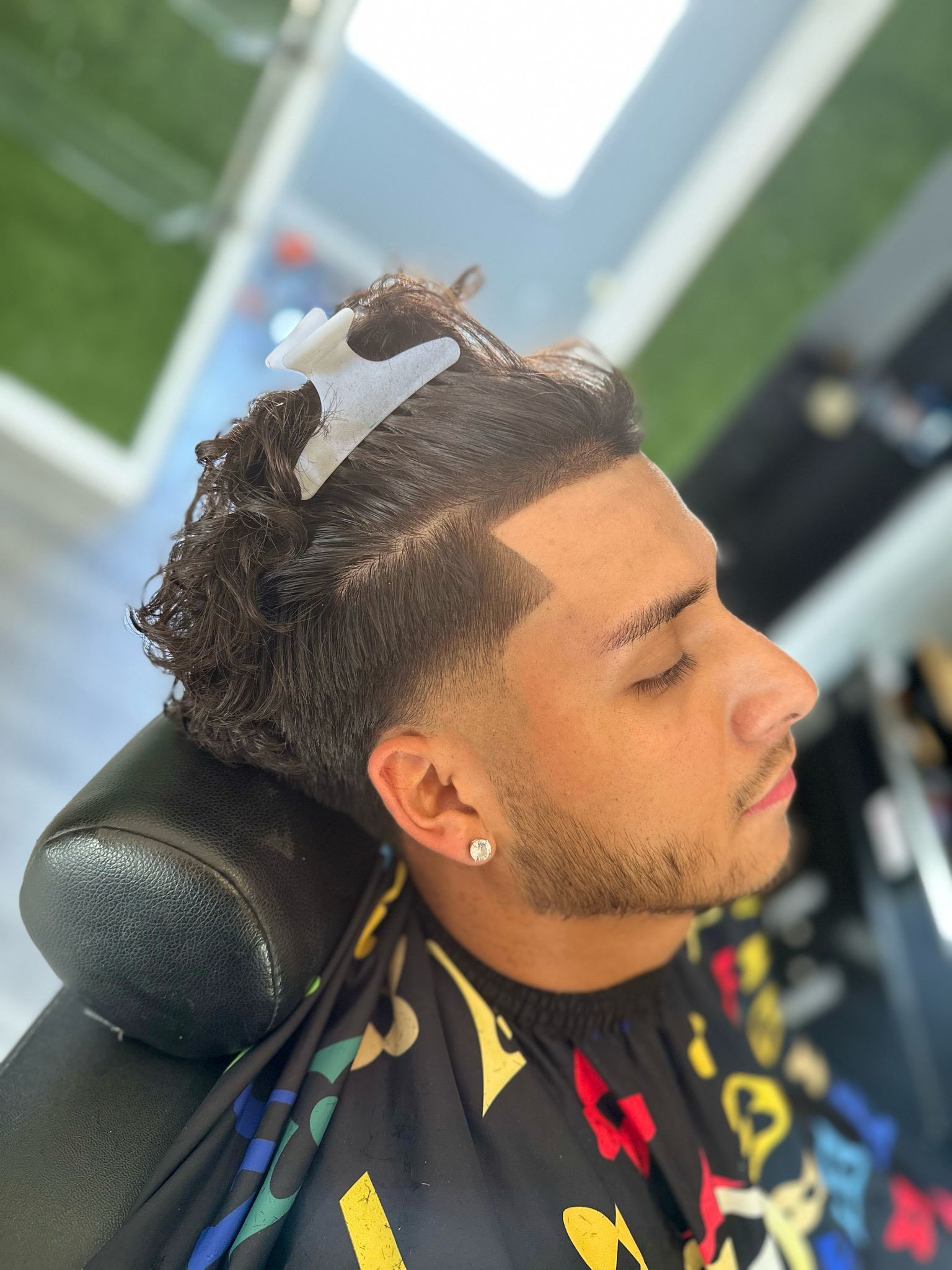 A man is getting his hair cut at a barber shop.