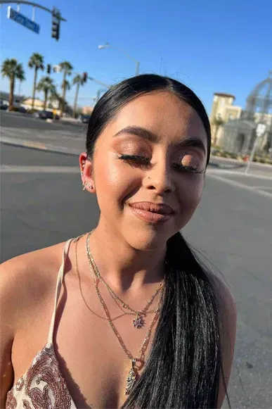 A woman is standing in the middle of a street wearing a necklace and smiling.