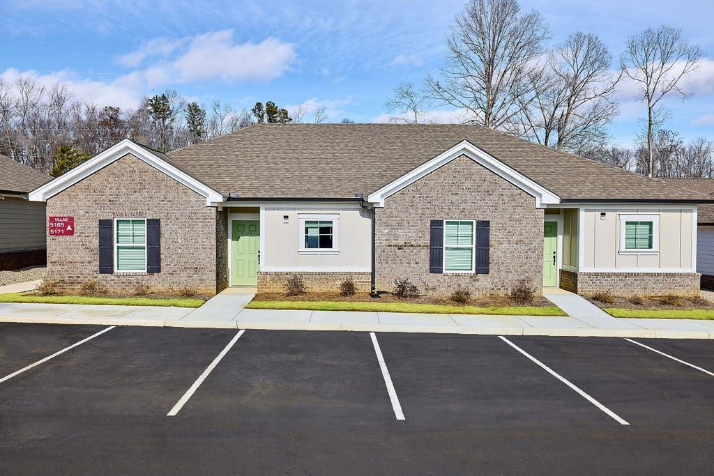 A row of houses with a parking lot in front of them.