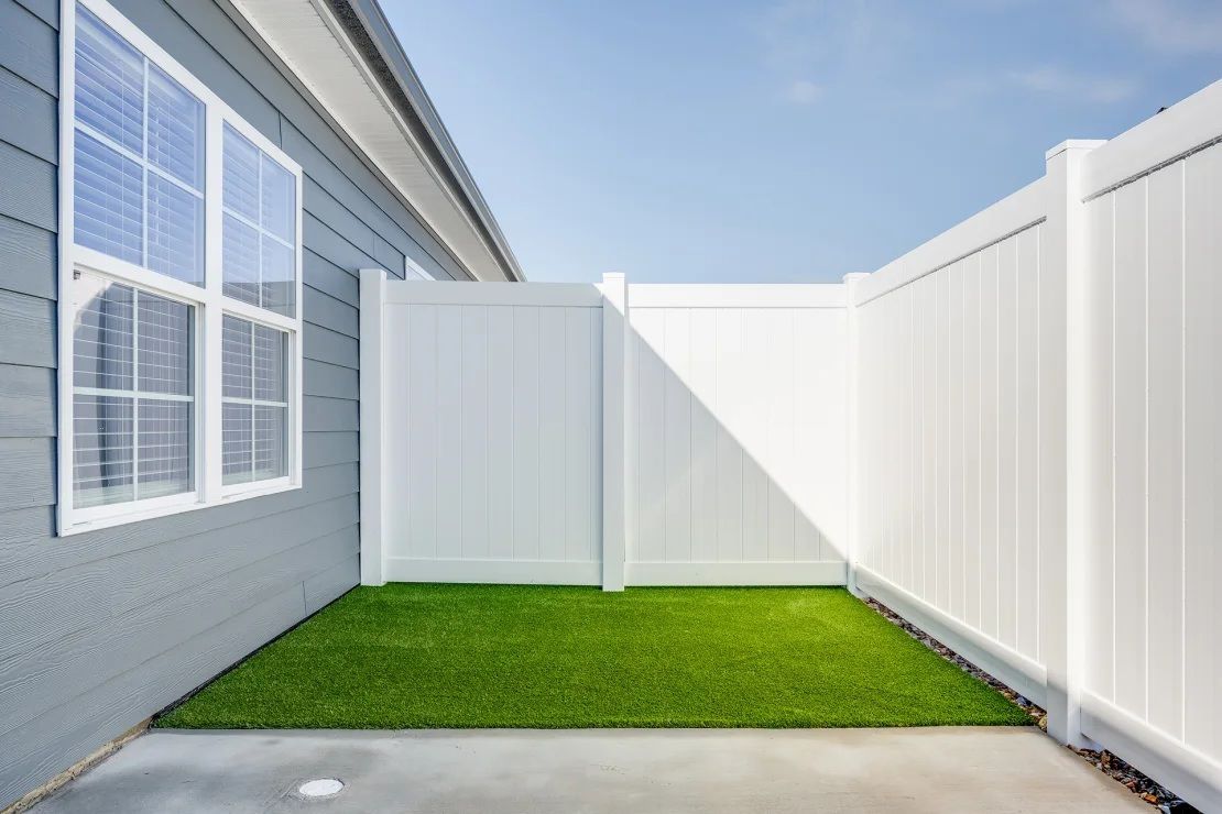 There is a white fence in the backyard of a house.