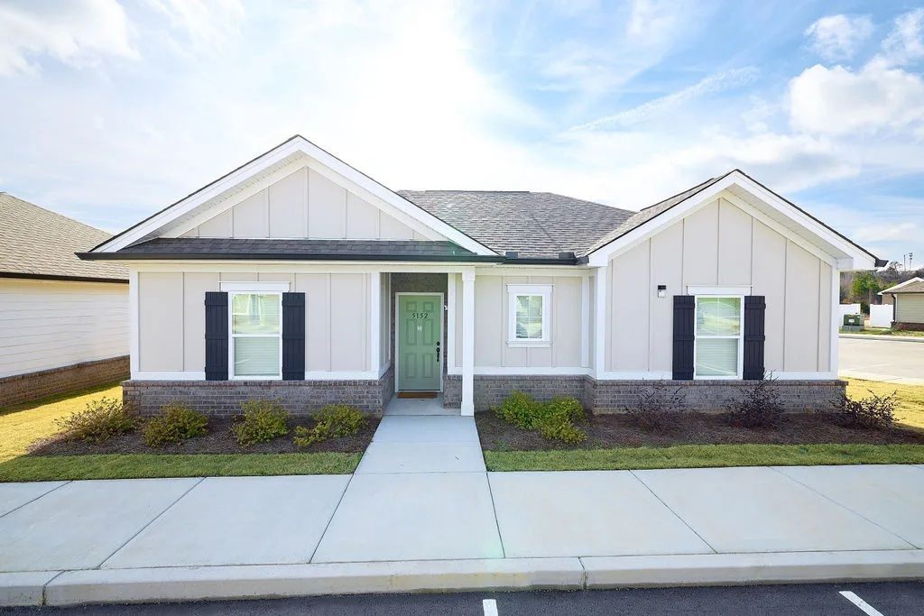 A white house with black shutters and a green door